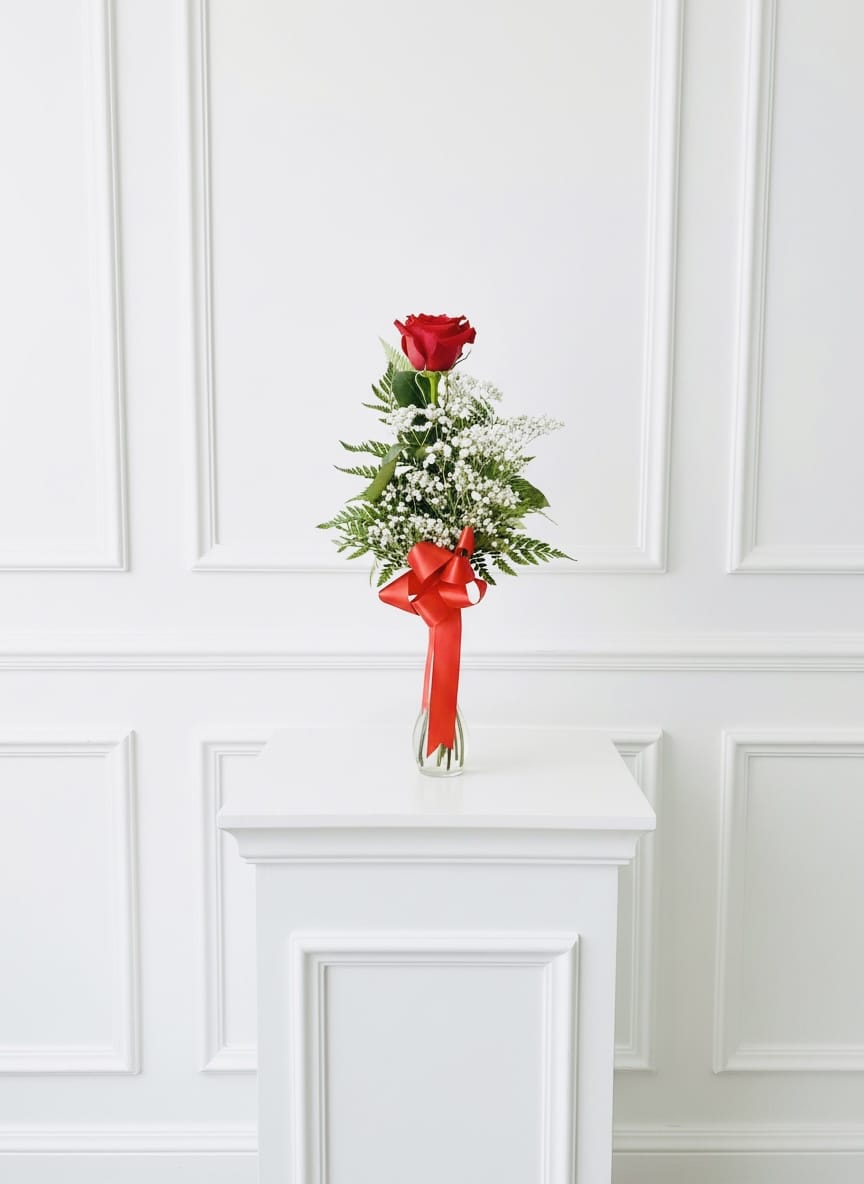 Single red rose in a clear vase with baby's breath and a red ribbon