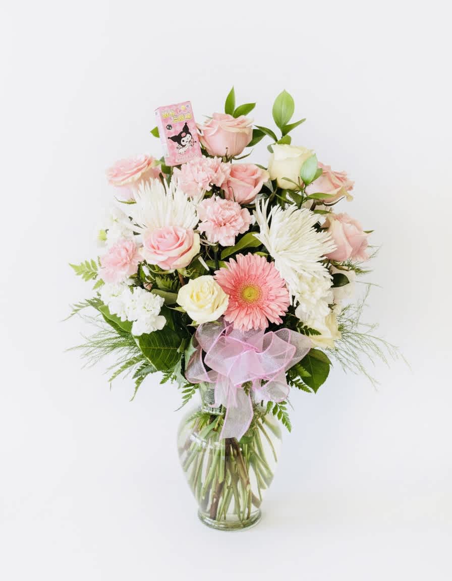 Pink and white mixed flower arrangement in a glass vase with a pink ribbon
