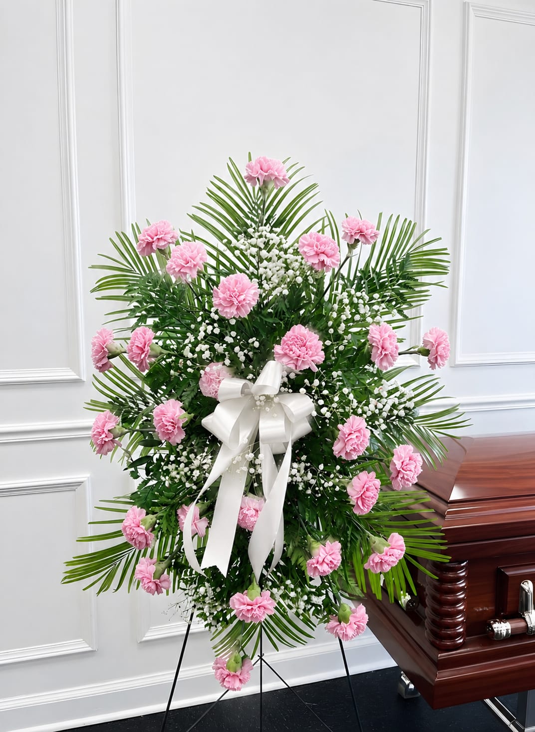 Graceful Remembrance Pink Carnation Standing Spray - Celebrate the memory of a loved one with our Graceful Remembrance Pink Carnation Standing Spray, a heartfelt expression of love, gratitude, and compassion. Designed with soft pink carnations, delicate baby's breath, fresh greenery, and an elegant satin ribbon, this standing funeral arrangement offers warmth and comfort during times of loss.  Pink carnations symbolize remembrance, admiration, gratitude, and unconditional love, making this standing spray a meaningful tribute for funeral services, memorials, celebrations of life, or visitation services. Handcrafted by experienced florists using premium fresh flowers, this arrangement serves as a beautiful reminder of a life that will always be remembered.  Perfect For:  Funeral Services Memorial Services Celebration of Life Sympathy Gifts Visitation &amp; Wake Services
