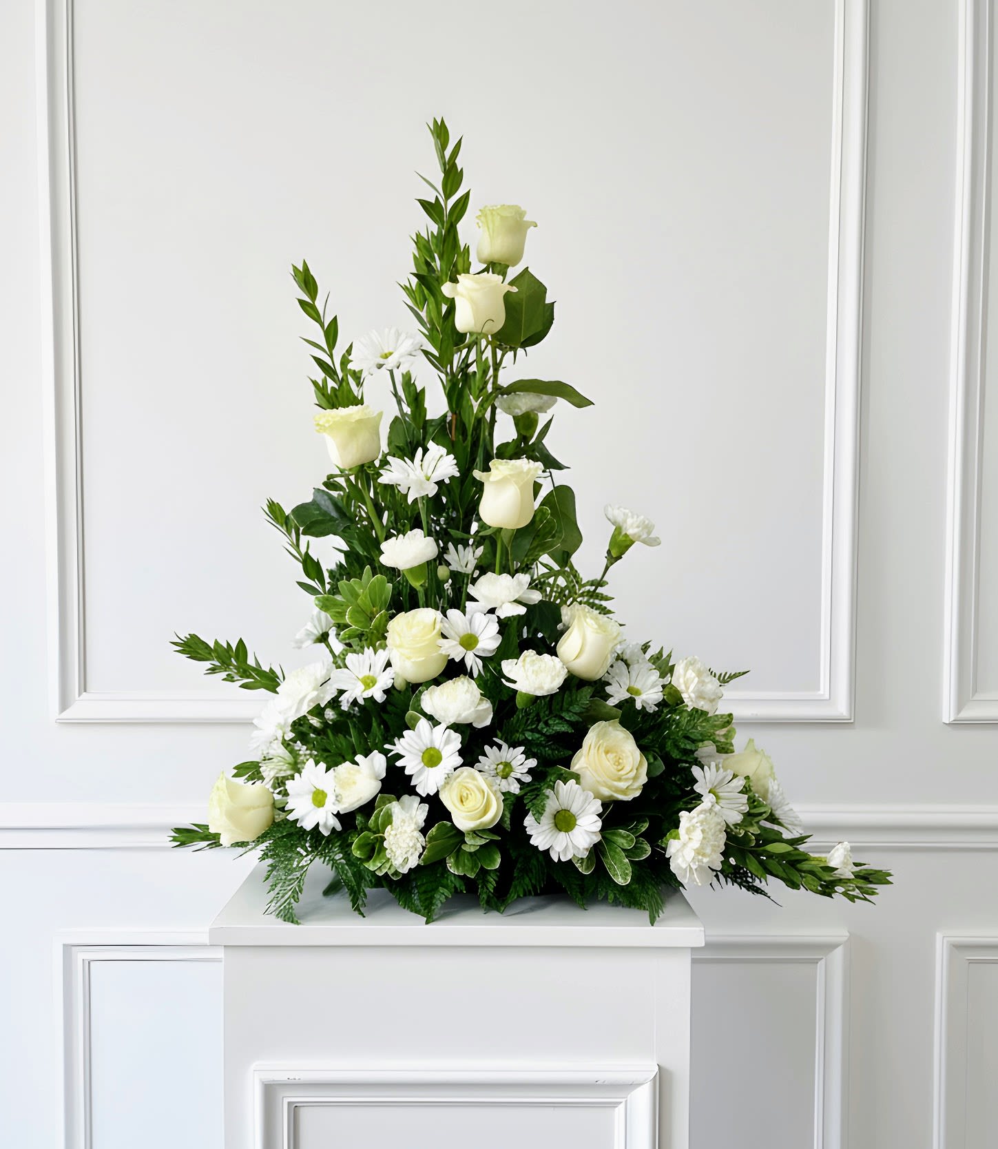 Pure Grace White Sympathy Arrangement - Express your heartfelt condolences with the timeless beauty of the Pure Grace White Sympathy Arrangement. Handcrafted with elegant white roses, fresh white daisies, carnations, and premium seasonal greenery, this classic sympathy tribute offers comfort, peace, and remembrance during life's most difficult moments.  Designed in a graceful triangular silhouette, this arrangement is ideal for funeral services, memorials, celebration of life ceremonies, or to send directly to the family's home.   Flowers may include: White Roses White Daisy Chrysanthemums White Carnations Premium Seasonal Greenery  Perfect For: Funeral Services Memorial Services Celebration of Life Sending Sympathy to the Home
