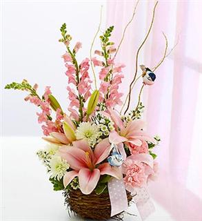Pink lilies and snapdragons in a wicker basket with a ribbon