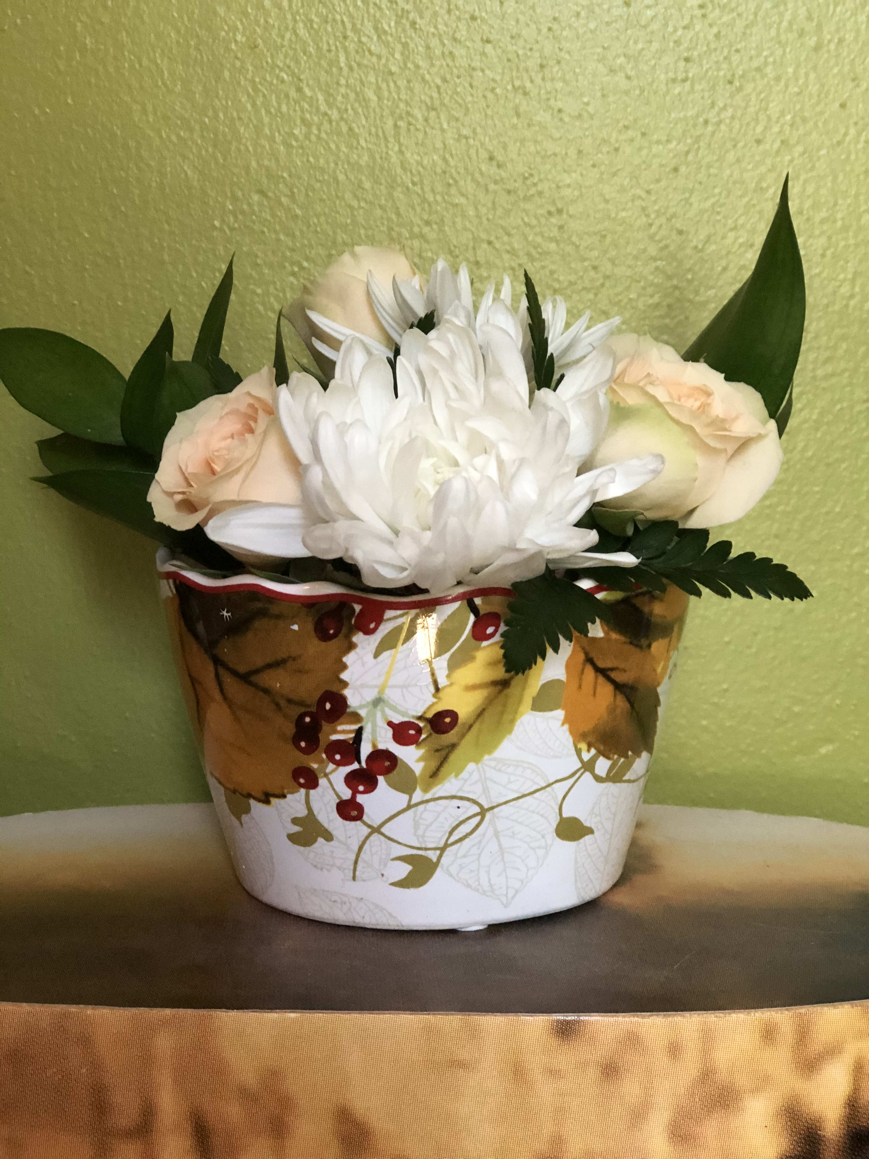 White and peach flowers arranged in a decorative autumn container