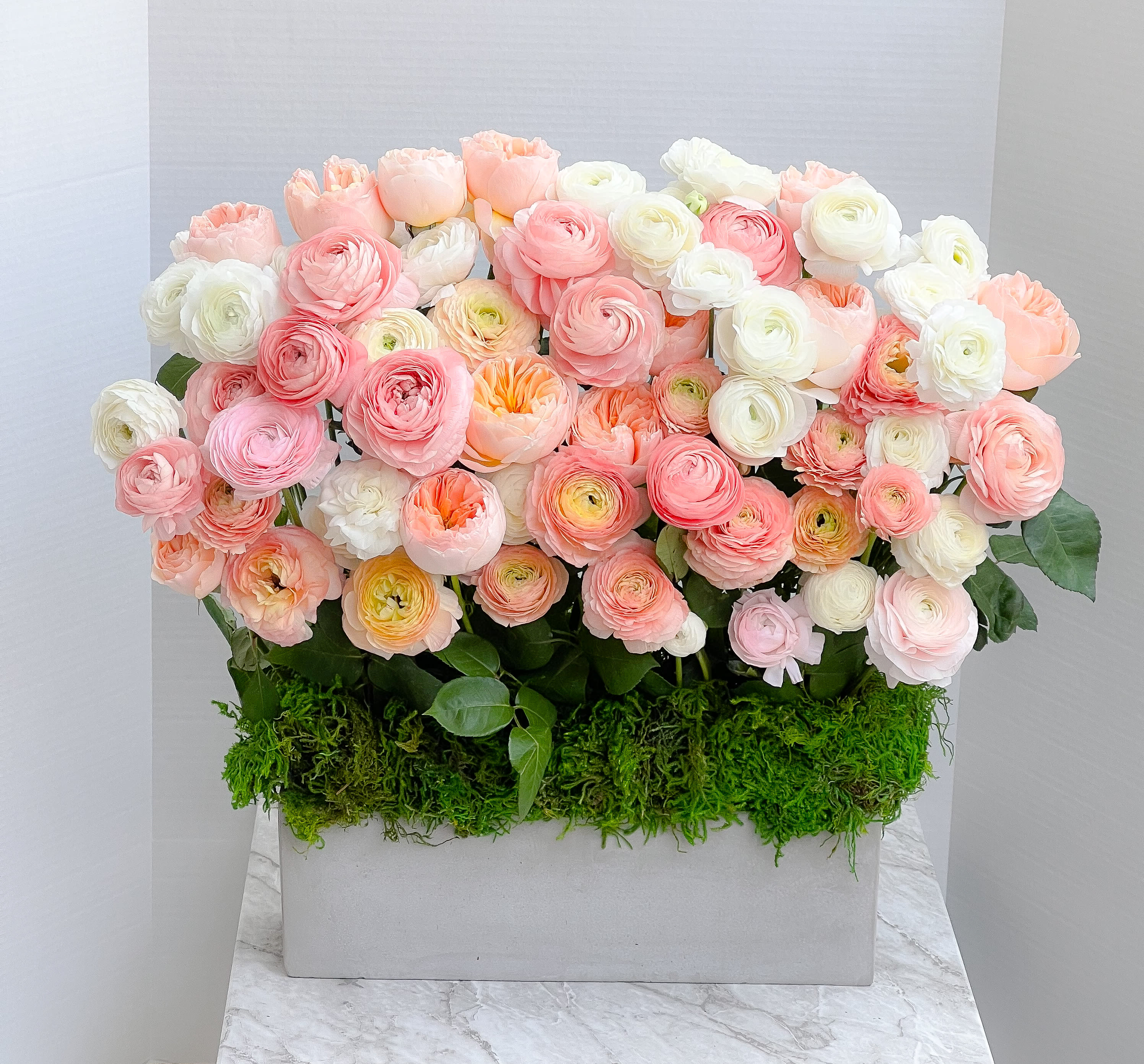 Box arrangement of pink, peach, and white ranunculus flowers