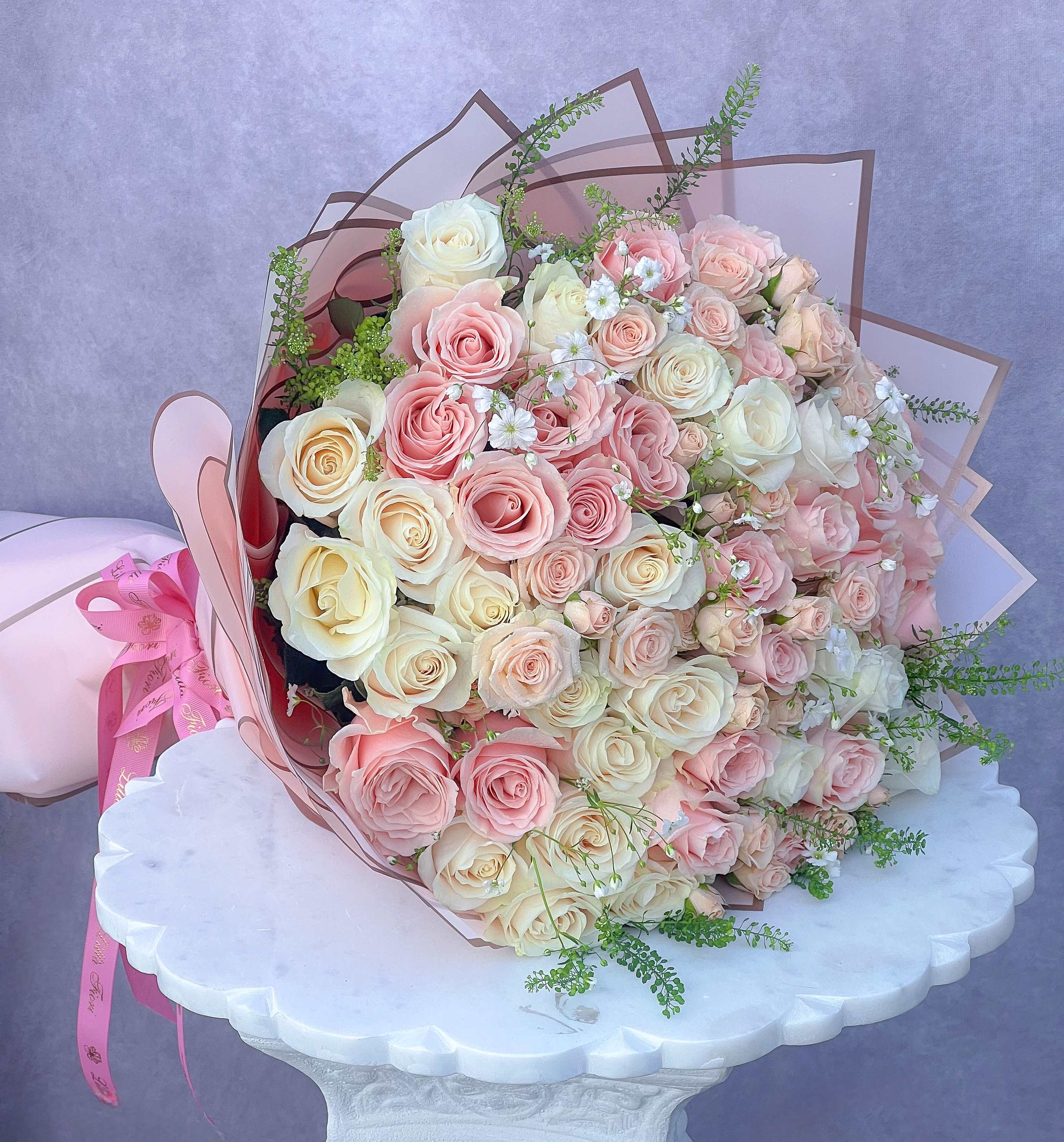 Large bouquet of pink and cream roses wrapped in pink paper