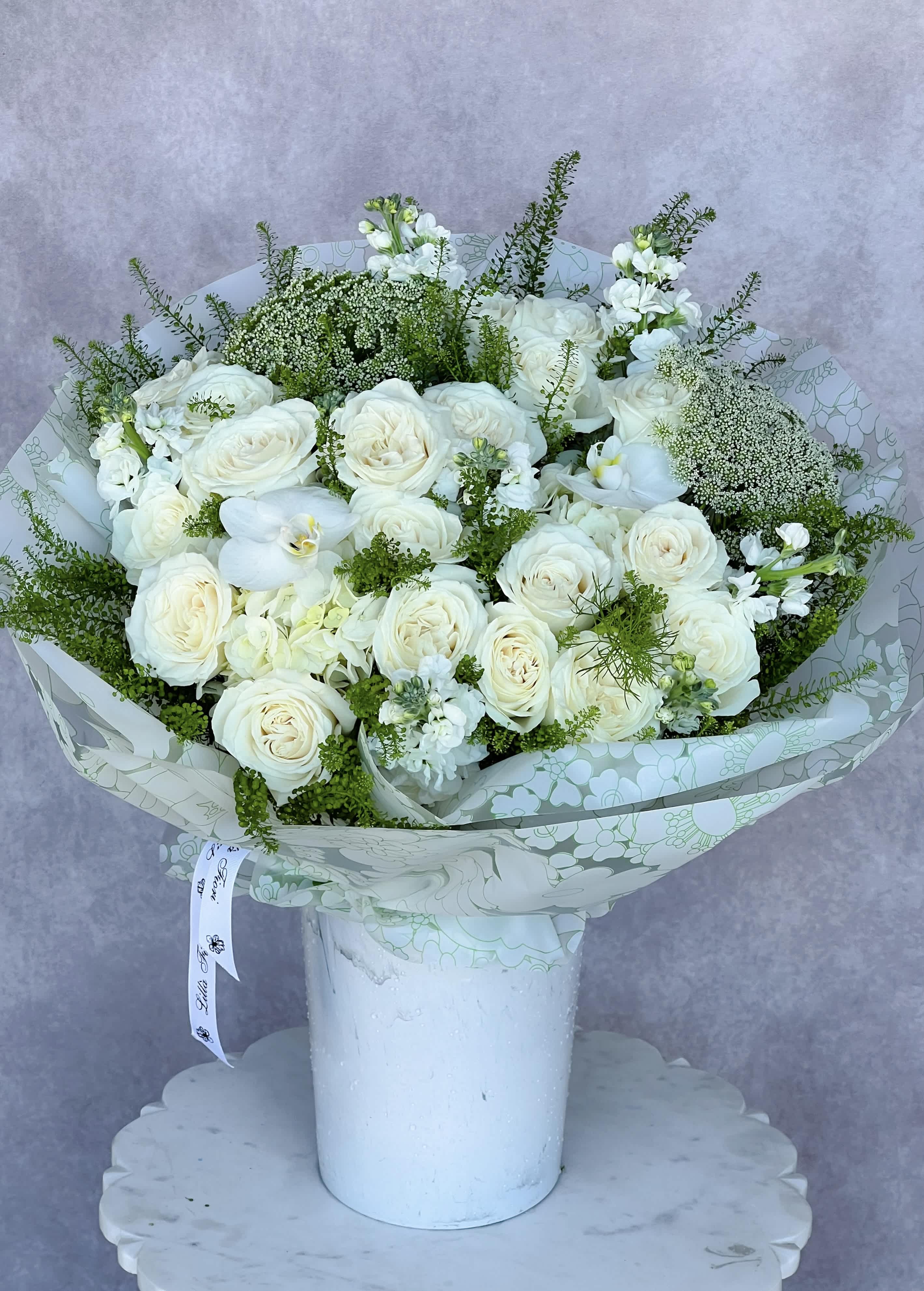 White rose bouquet with orchids in a white vase