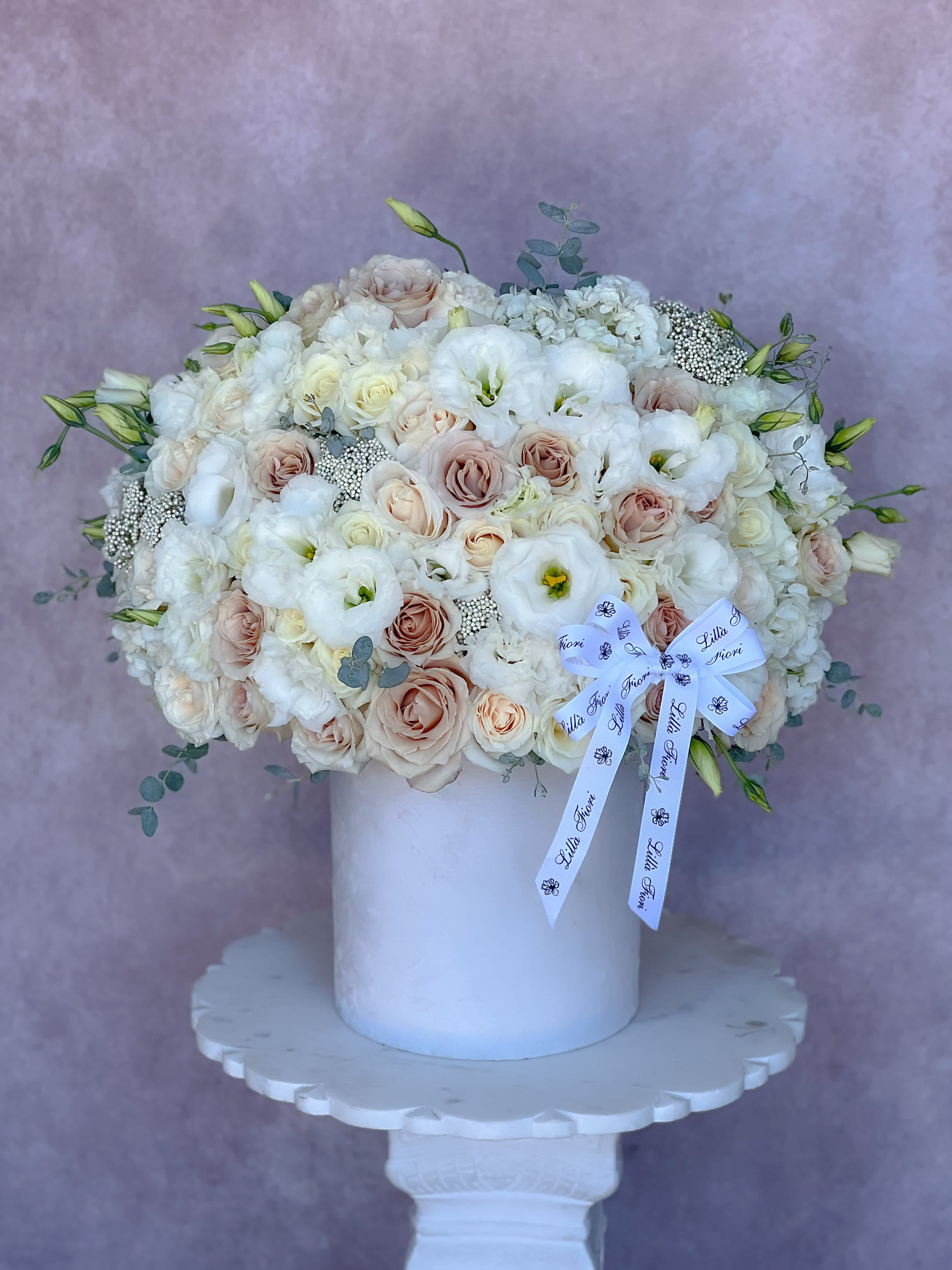 Large white and blush bouquet in a white vase with a ribbon bow