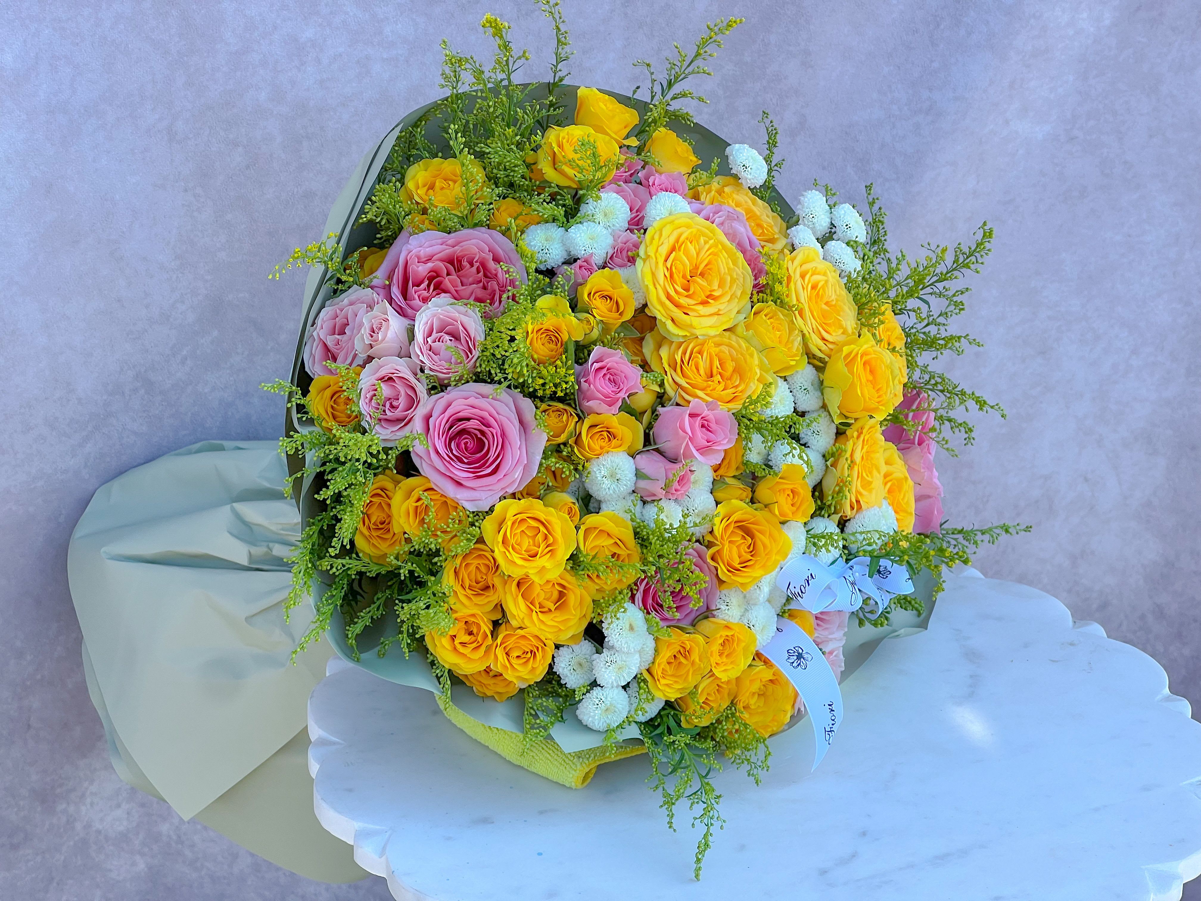 Bouquet of yellow and pink roses with small white flowers
