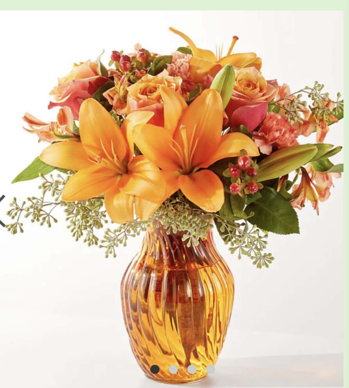 Orange lilies and peach roses arranged in an amber glass vase