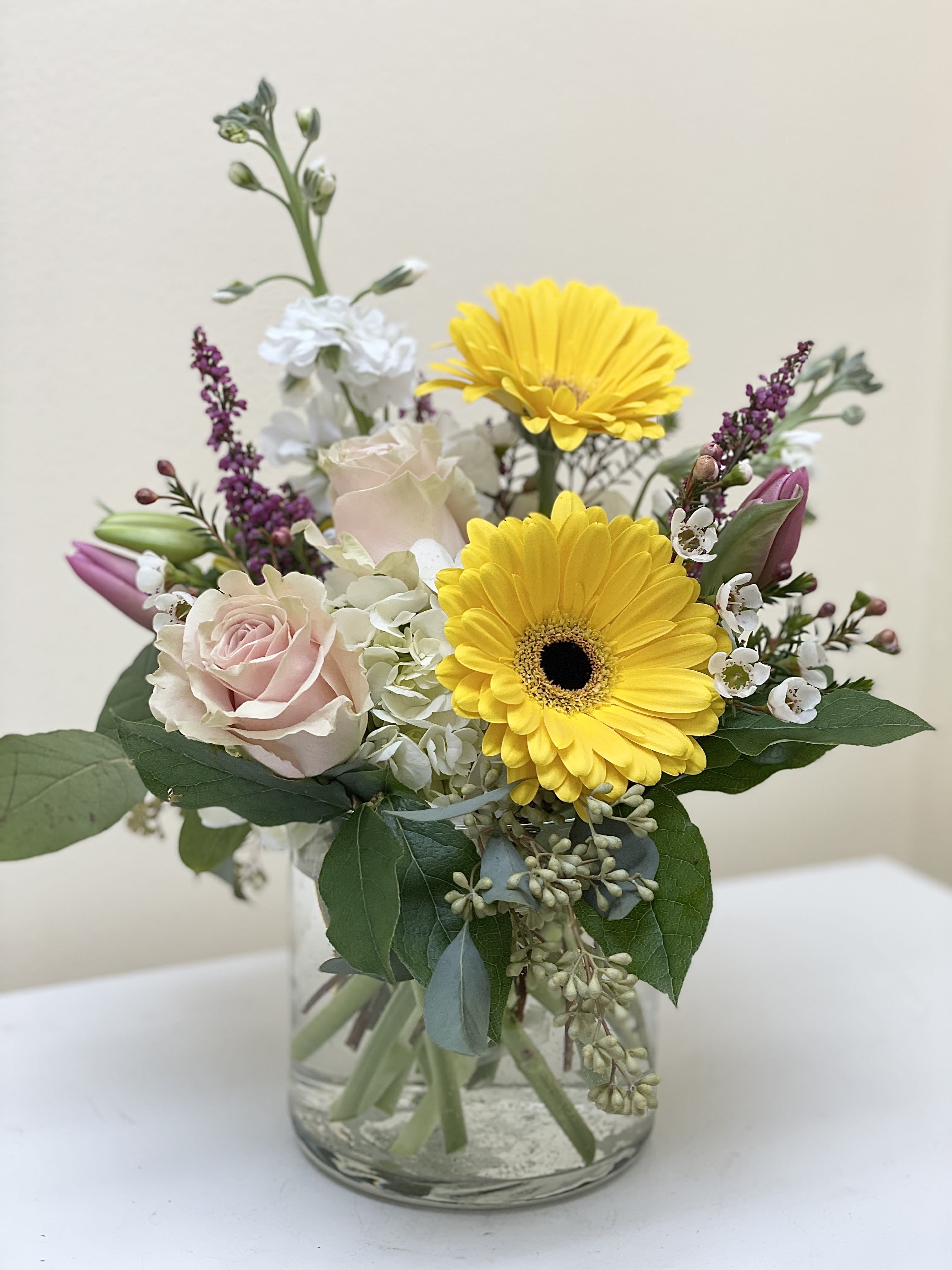 Bouquet of yellow gerbera daisies and pale pink roses in a glass vase