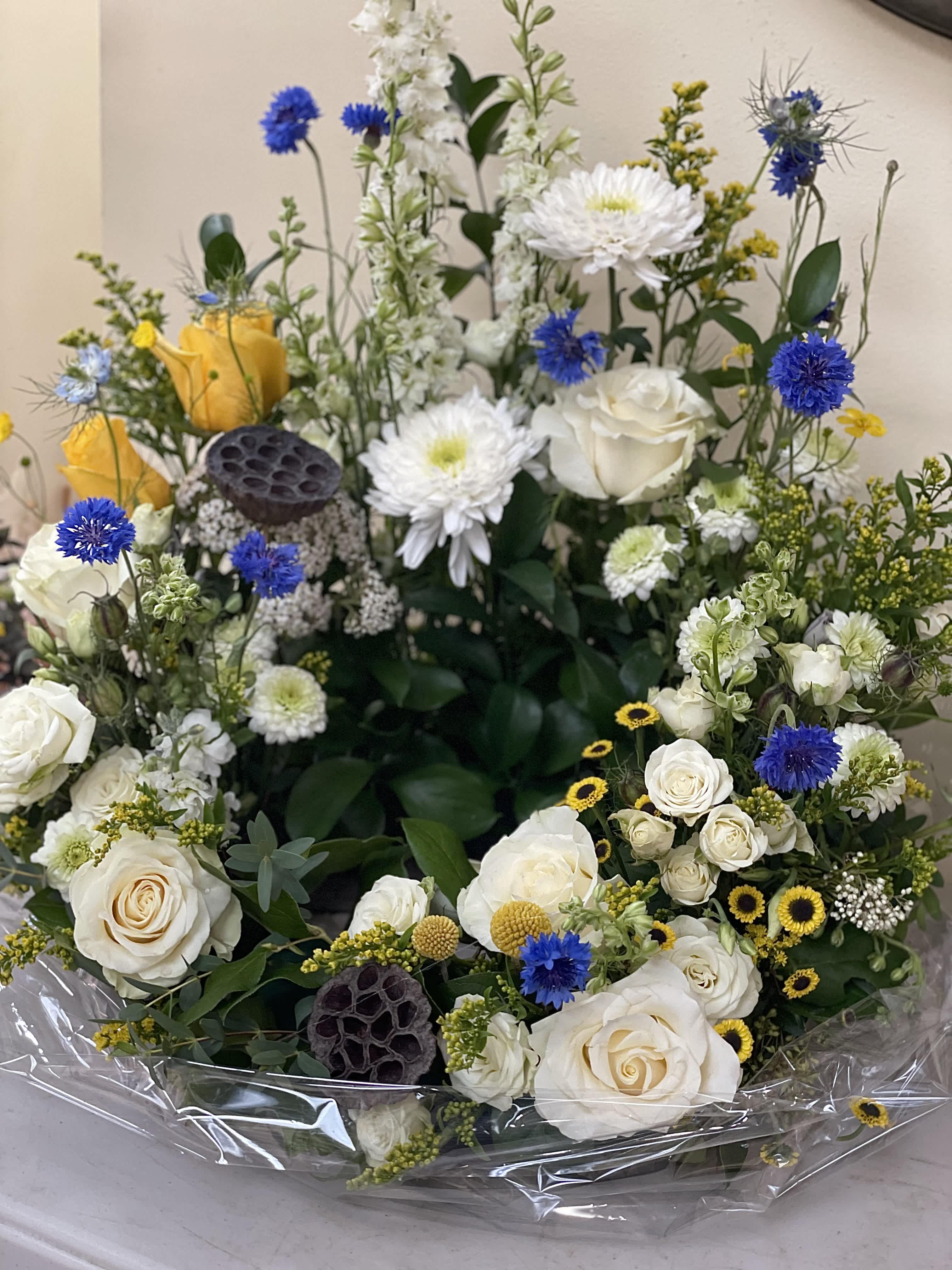 White roses and chrysanthemums with blue accents in a wrapped bouquet