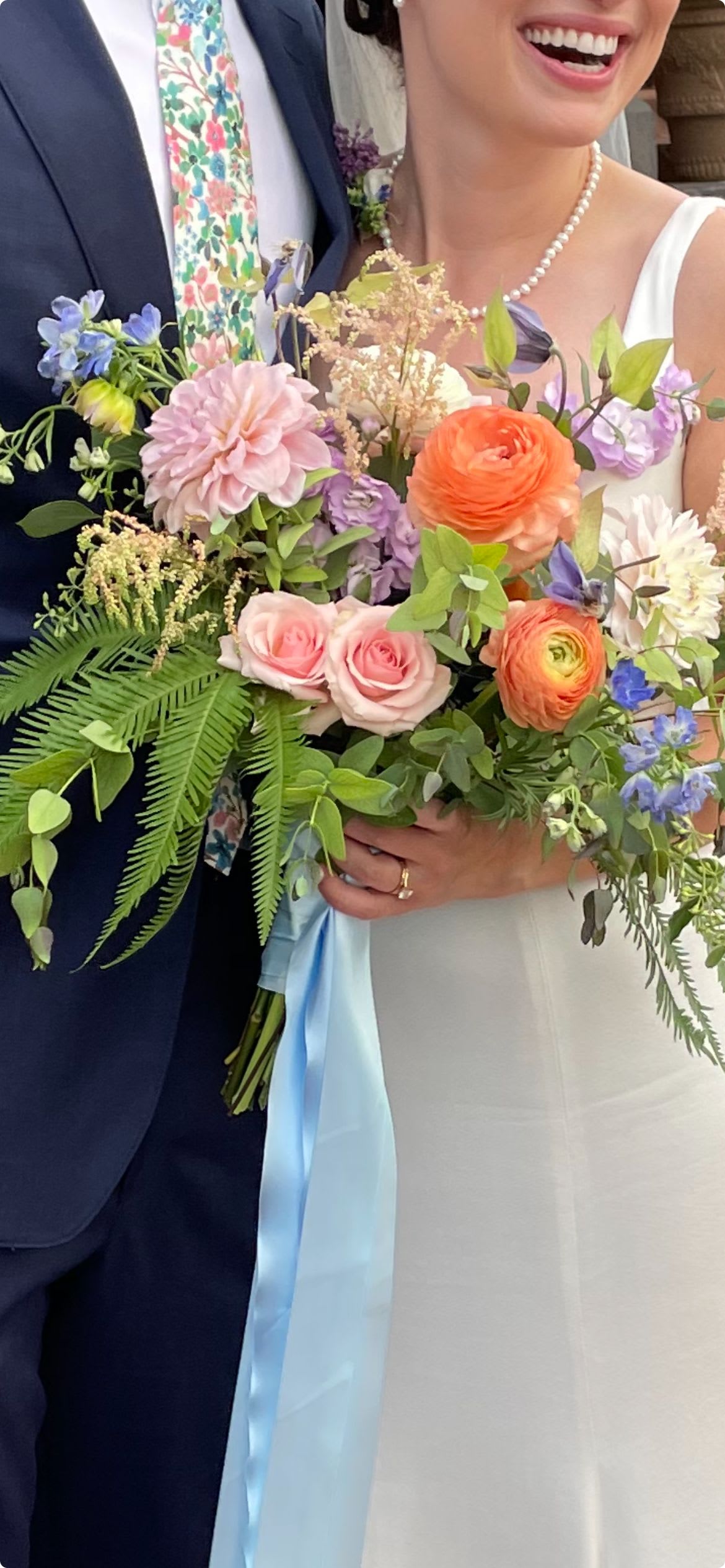 Bride and groom holding pastel wedding bouquets with roses and ranunculus