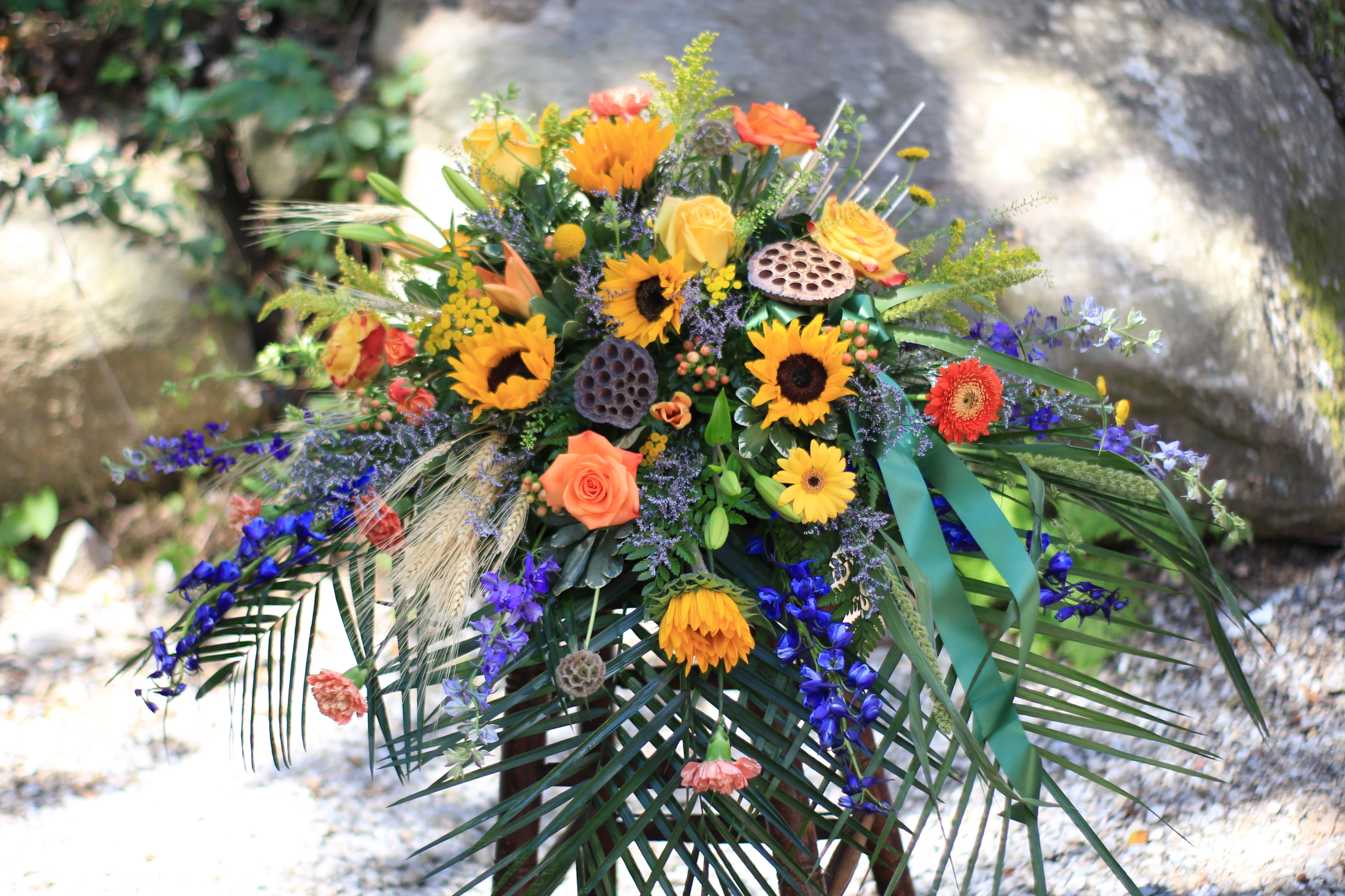 Colorful floral spray with sunflowers, roses, and blue flowers