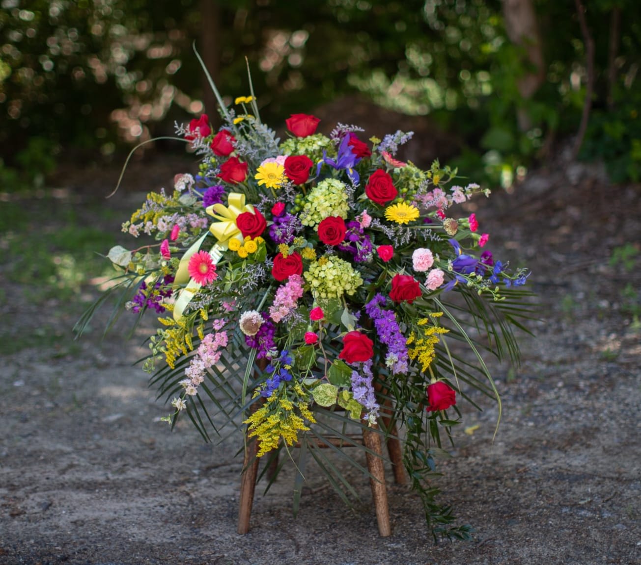 Large colorful floral spray with red roses on a wooden stand