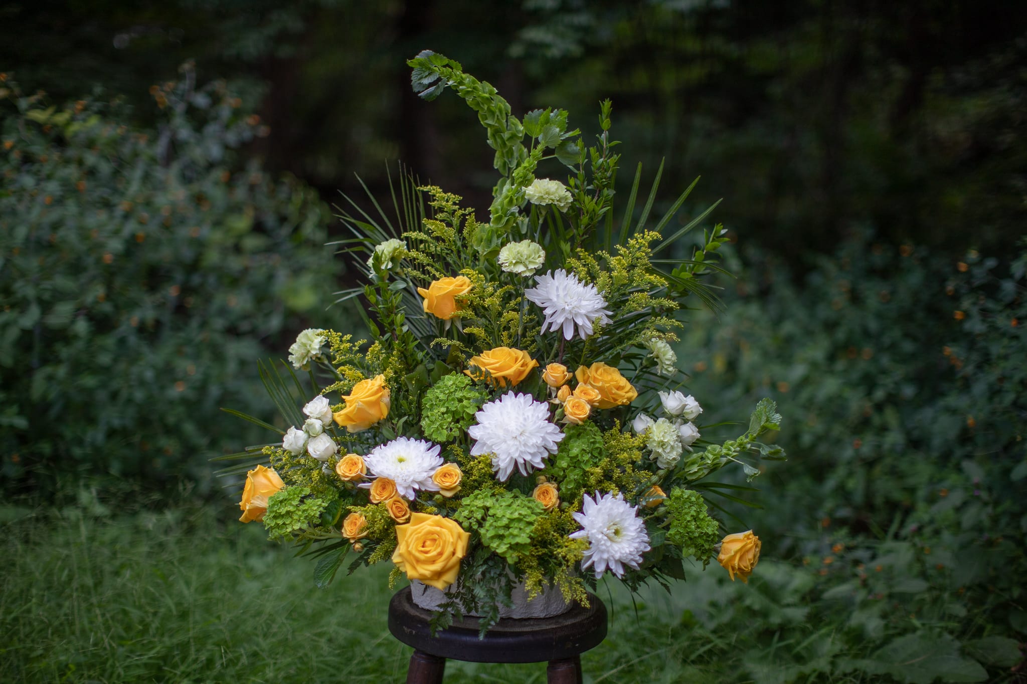 Yellow and white floral arrangement in a vase with greenery
