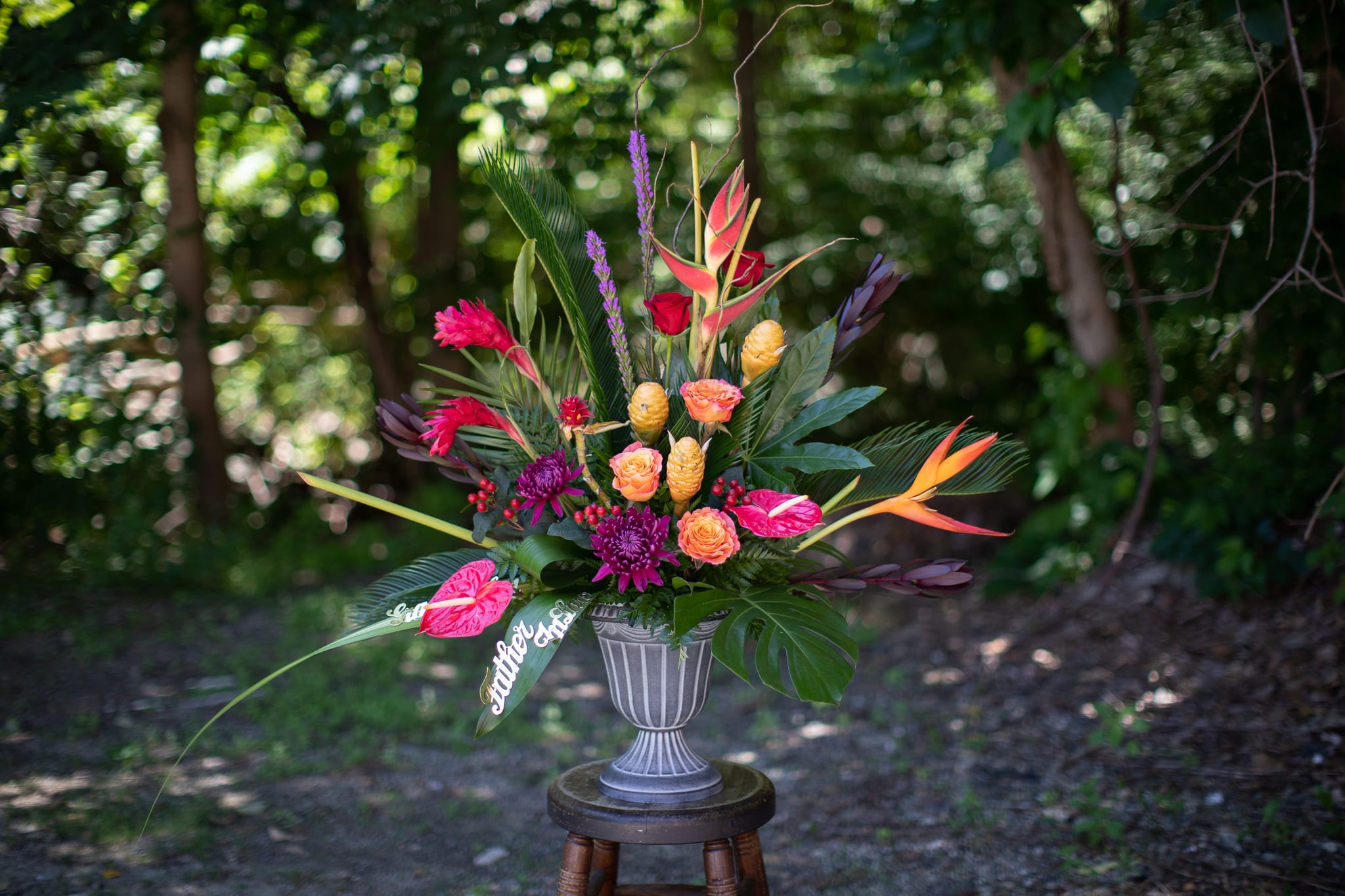 Tropical floral arrangement in a gray urn vase with bright pink and orange blooms