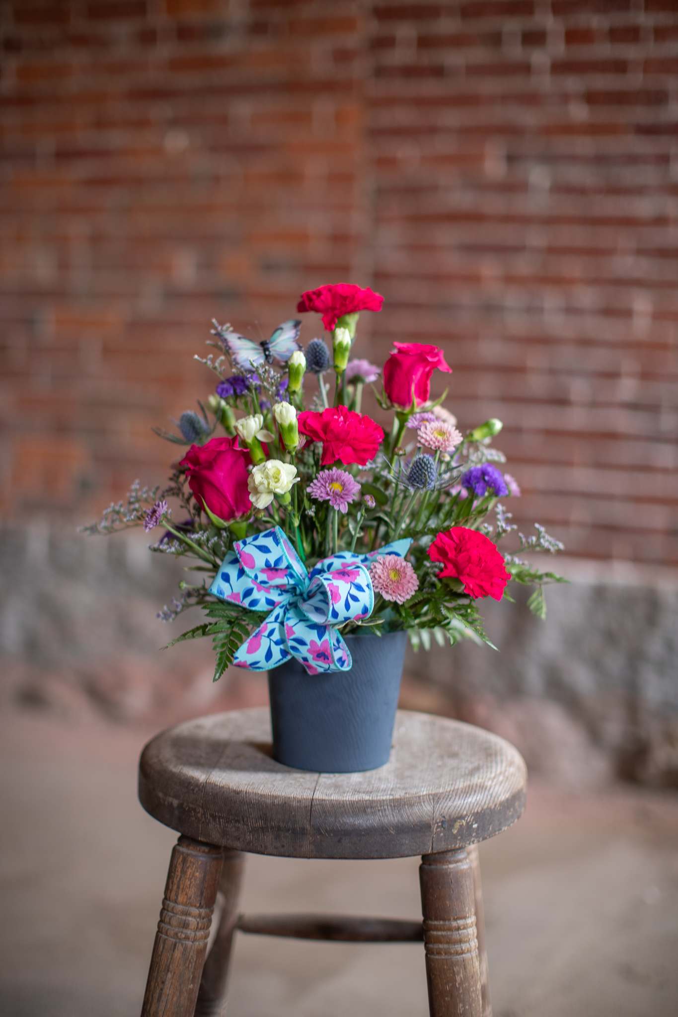 Bright mixed bouquet in a blue pot with a patterned bow