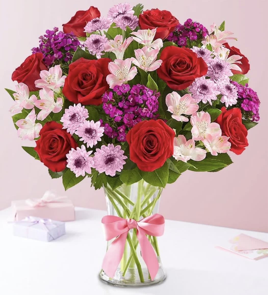 Bouquet of red roses, pink alstroemeria, and purple flowers in a glass vase