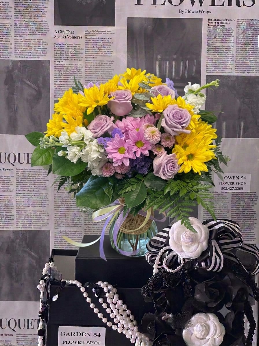 Bouquet of yellow daisies and lavender roses in a glass vase