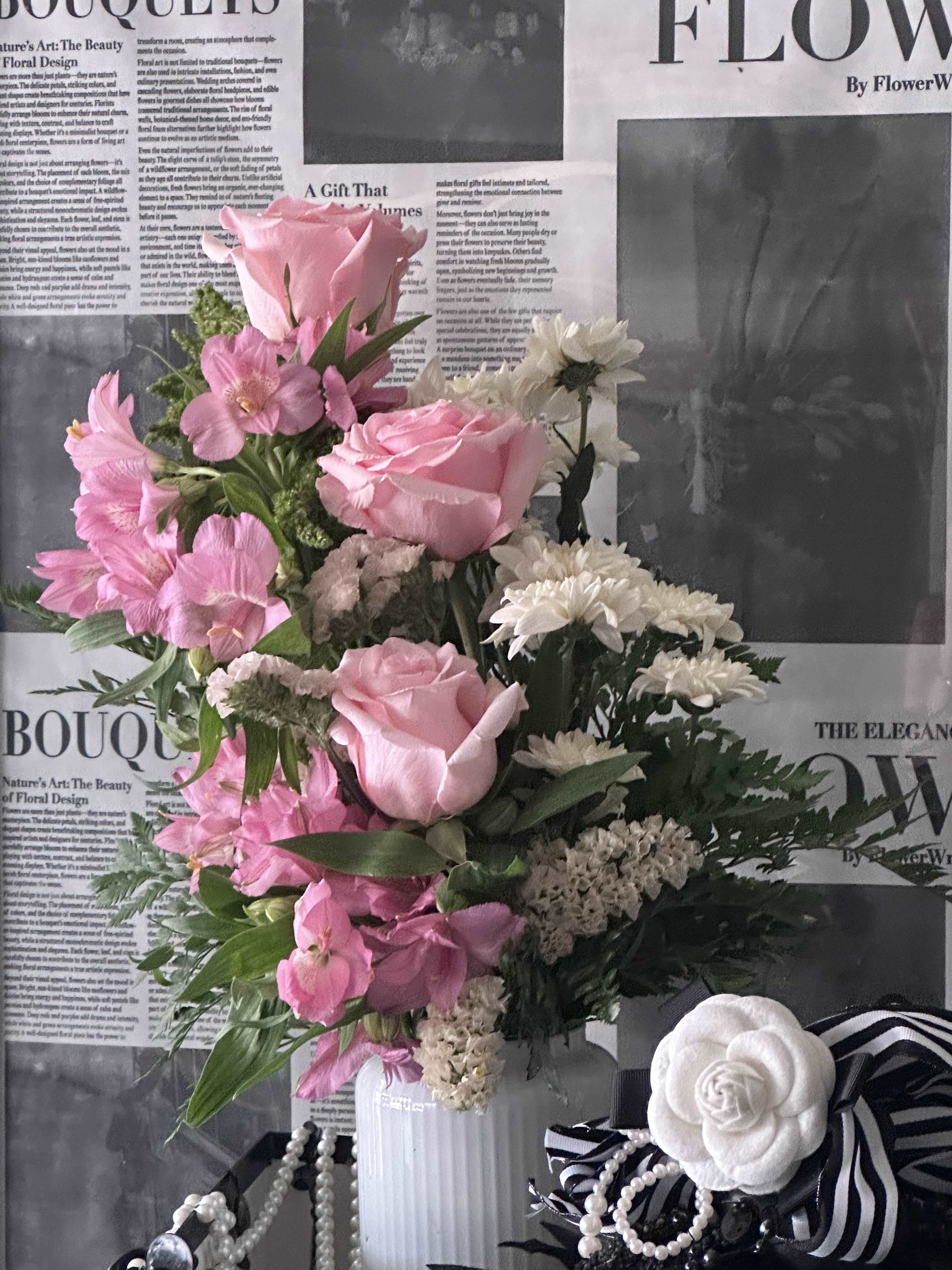 Pink and white floral arrangement in a white vase with ribbon accents