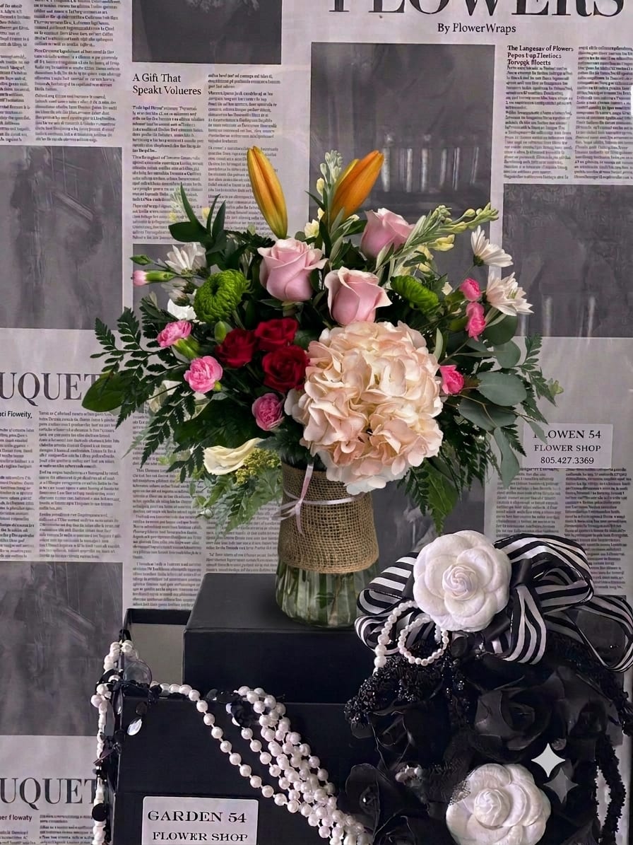 Mixed bouquet in a glass vase with pink roses, lilies, and hydrangea