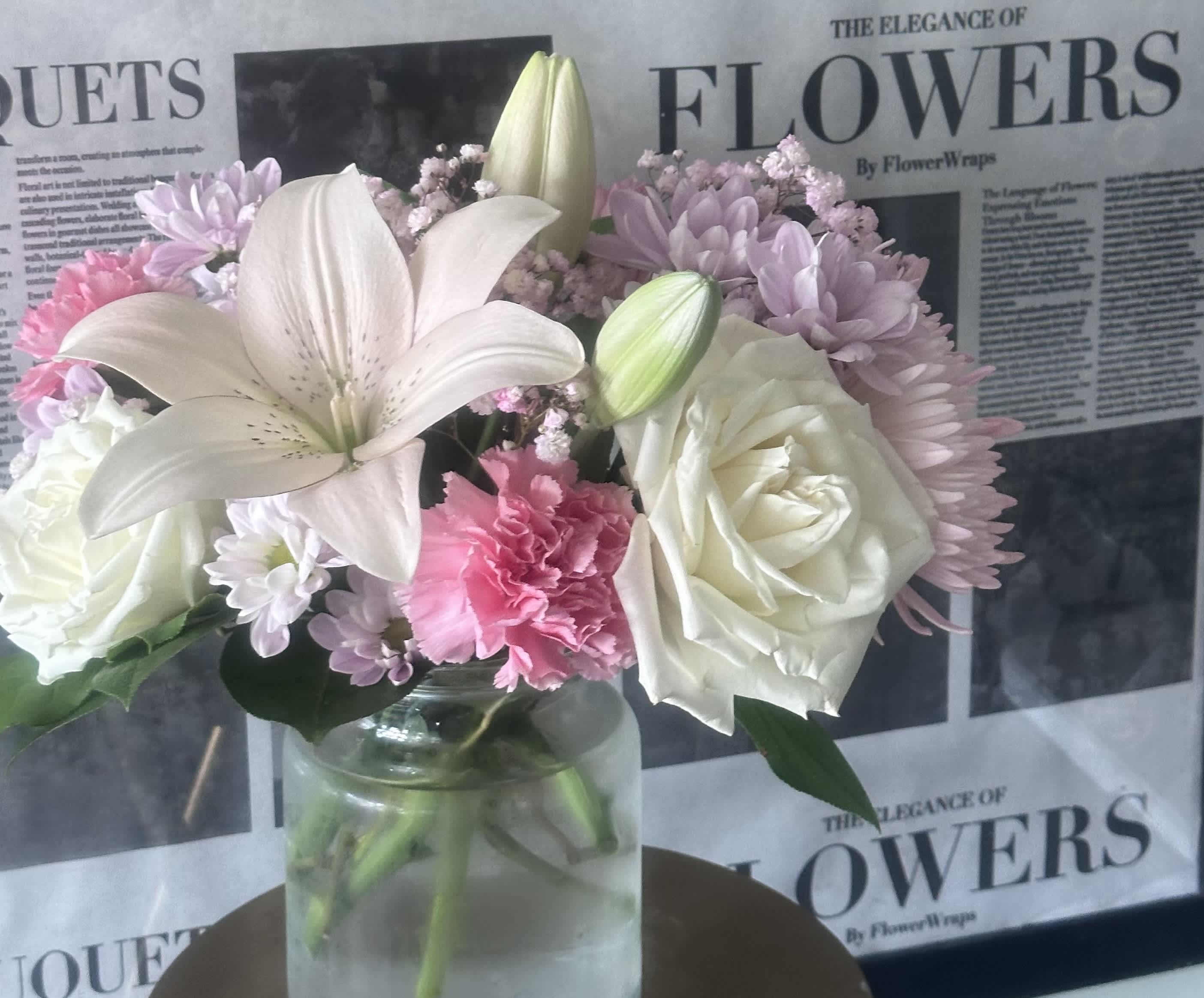Bouquet of white lilies, roses, and pink flowers in a glass vase