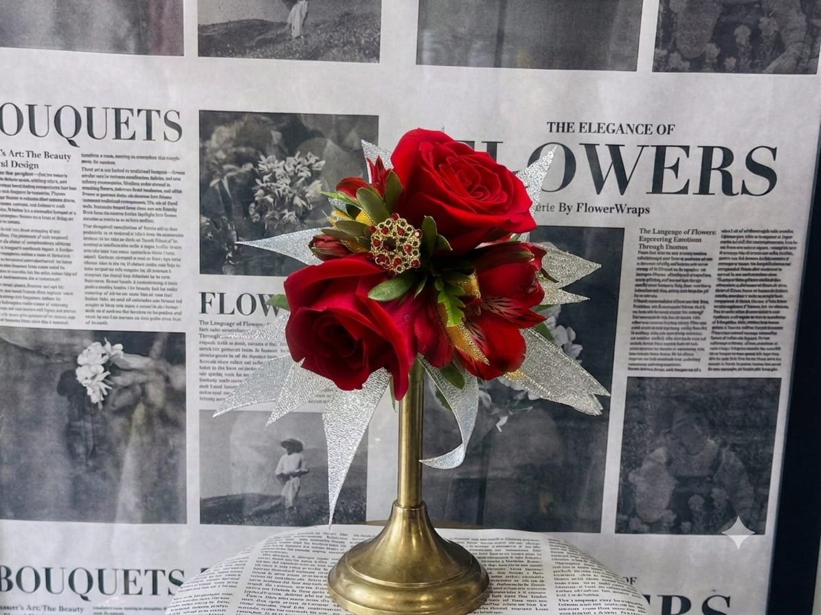Red rose bouquet in a gold trumpet vase with silver ribbon accents