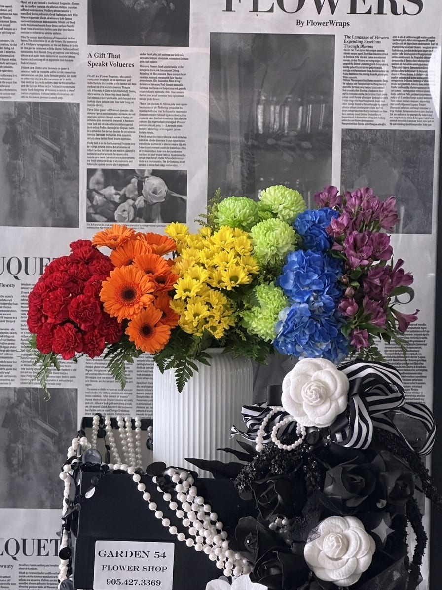 Colorful mixed flower arrangement in a white vase with black-and-white ribbon accents