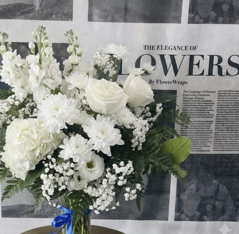 White floral bouquet in a glass vase with a blue ribbon