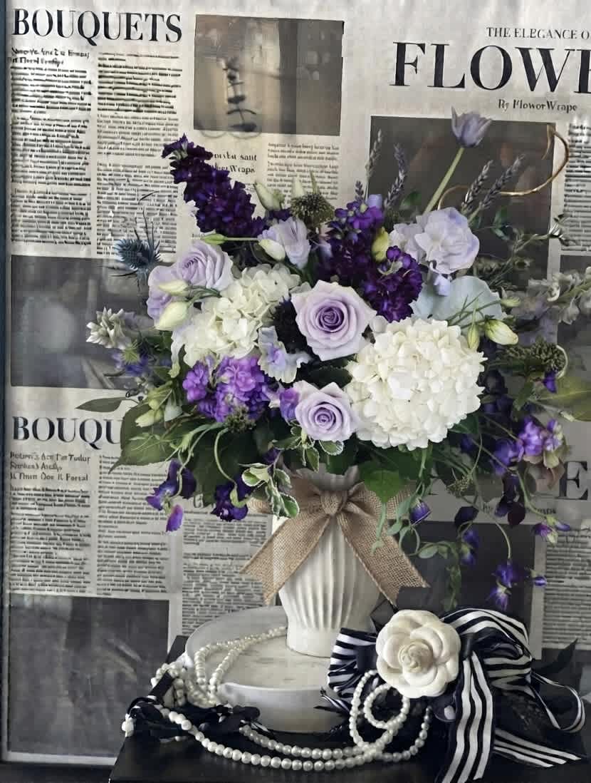 Lavender and white bouquet in a white vase with a burlap bow