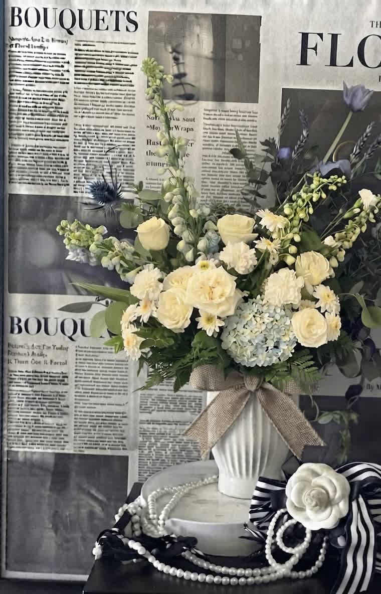 Cream and pale blue bouquet in a white vase with a burlap bow