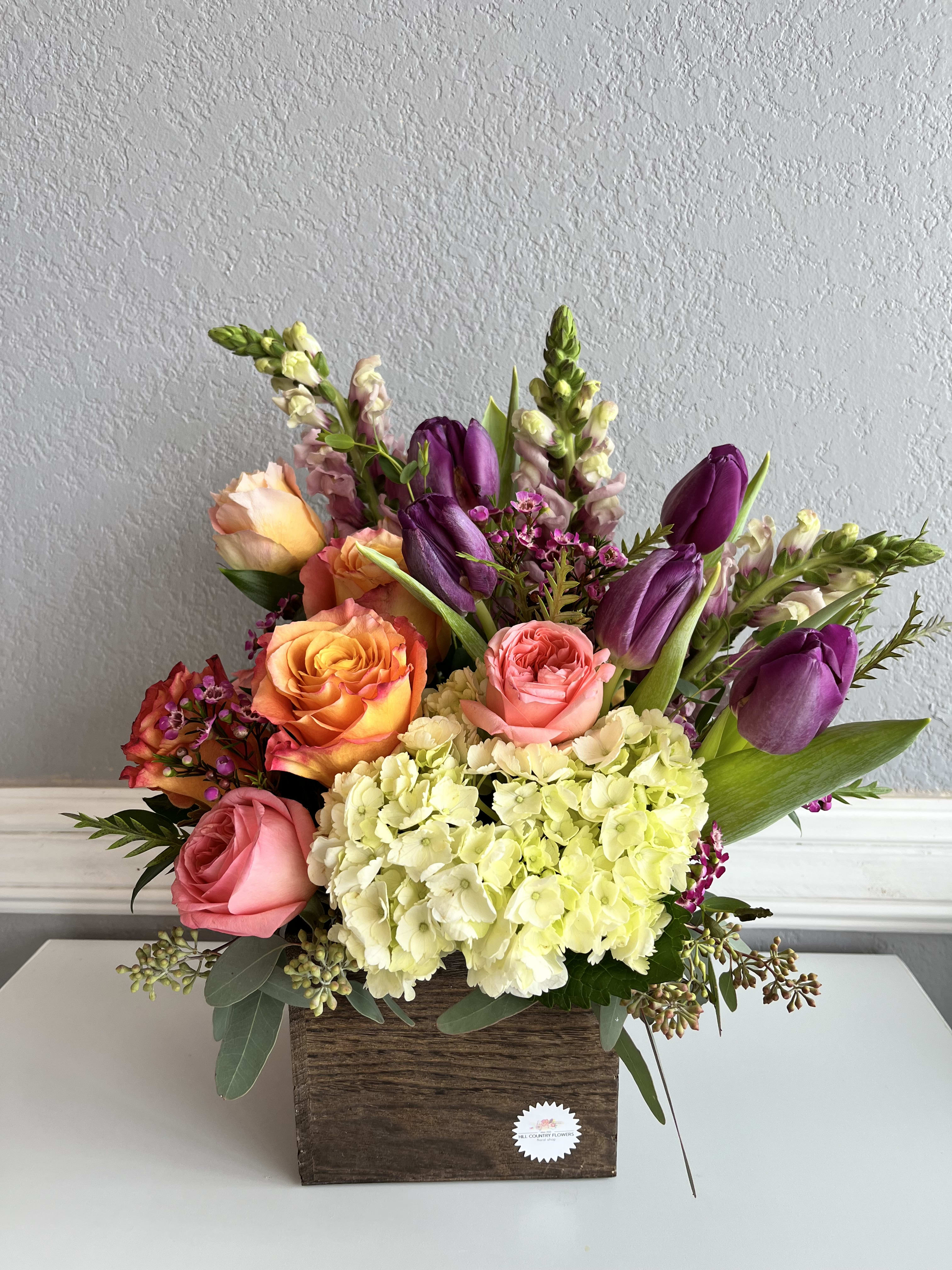 Mixed bouquet of roses, tulips, and hydrangeas in a wooden box