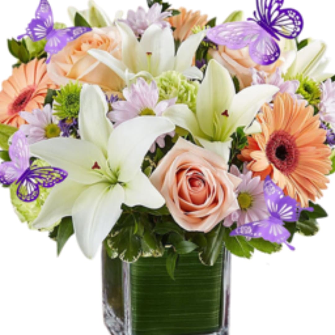 Mixed bouquet of lilies, roses, and daisies in a square glass vase
