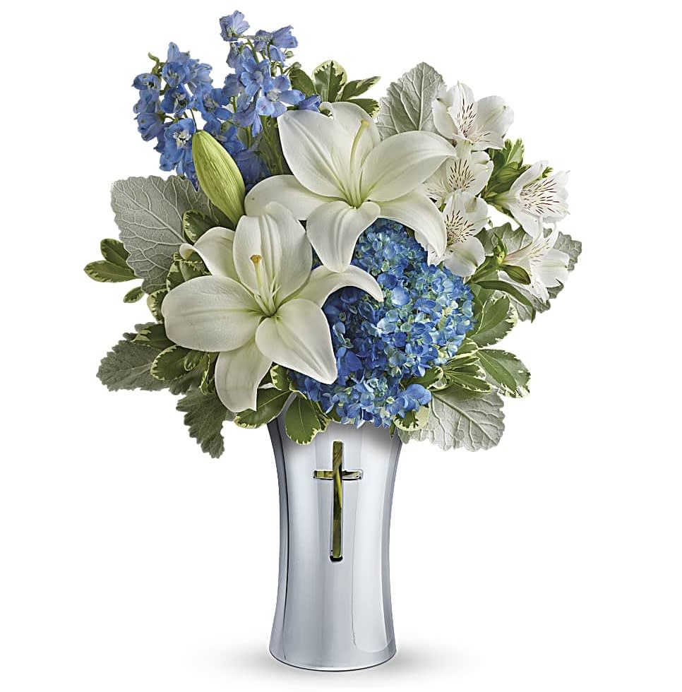 Skies Of Remembrance Bouquet - An elegant expression of your deepest condolences, this majestic mix of blue hydrangea and white lilies will refresh and rejuvenate their spirits. It's hand-delivered in a shining, silver-finished ceramic vase with cross cut-out - a serene, spiritual keepsake they'll always treasure.