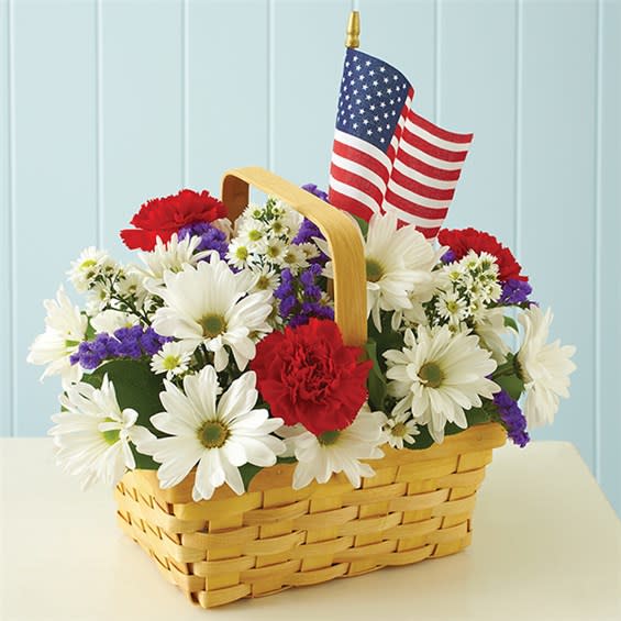 Red, White &amp; Blooms - Send a perfectly patriotic salute with this all-American basket arrangement of red carnations, white daisy poms, purple statice and white monte casino, accented with a true-blue, mini American flag and a festive ribbon. A hand-designed surprise that's ideal for patriotic holidays, as well as picnics and Summer get-togethers.