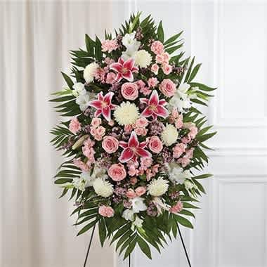 Pink &amp; White Sympathy Standing Spray - The warmth and kindness they showed will live on forever, and sometimes this sentiment is best captured through flowers. Our impressive standing spray arrangement, meticulously handcrafted by expert local florists with soothing pink and white blooms for a lush, full presentation, creates a truly memorable tribute.  •Standing spray arrangement with pink roses, spray roses, Stargazer lilies, Peruvian lilies (alstroemeria), carnations and waxflower; white gladiola and football mums; accented with soft, lush greenery  •Large measures approximately 56"H x 38"L without stand •Medium measures approximately 46"H x 34"L without stand  •Small measures approximately 42"H x 30"L without stand  •Arrives on an easel  •Appropriate for the funeral home or gravesite •Our florists use only the freshest flowers available, so colors and varieties may vary due to local availability