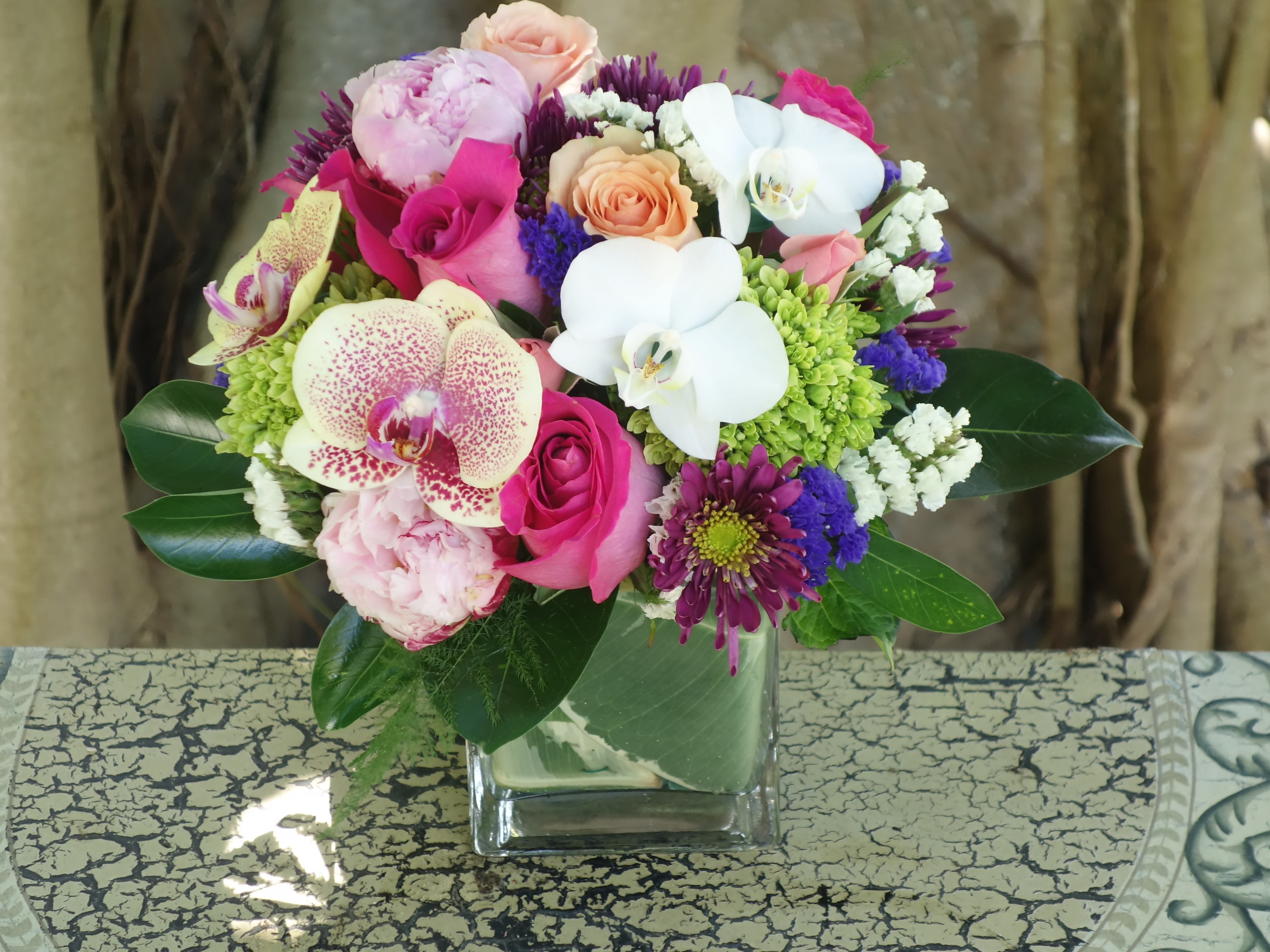 Mixed bouquet with orchids, roses, and chrysanthemums in a glass vase