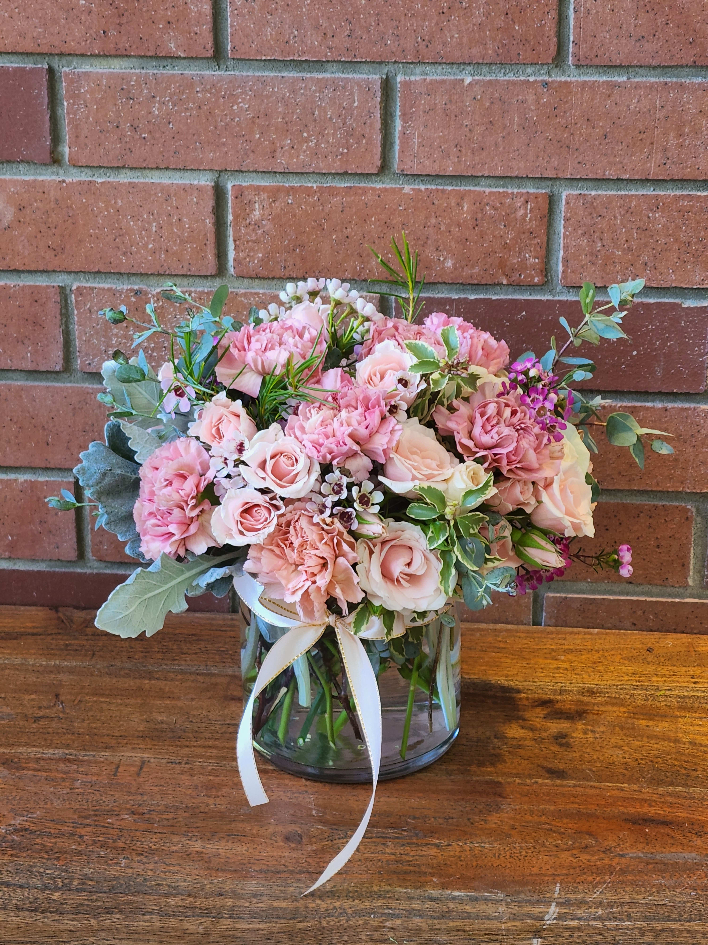 Pink and blush bouquet in a glass vase with a white ribbon