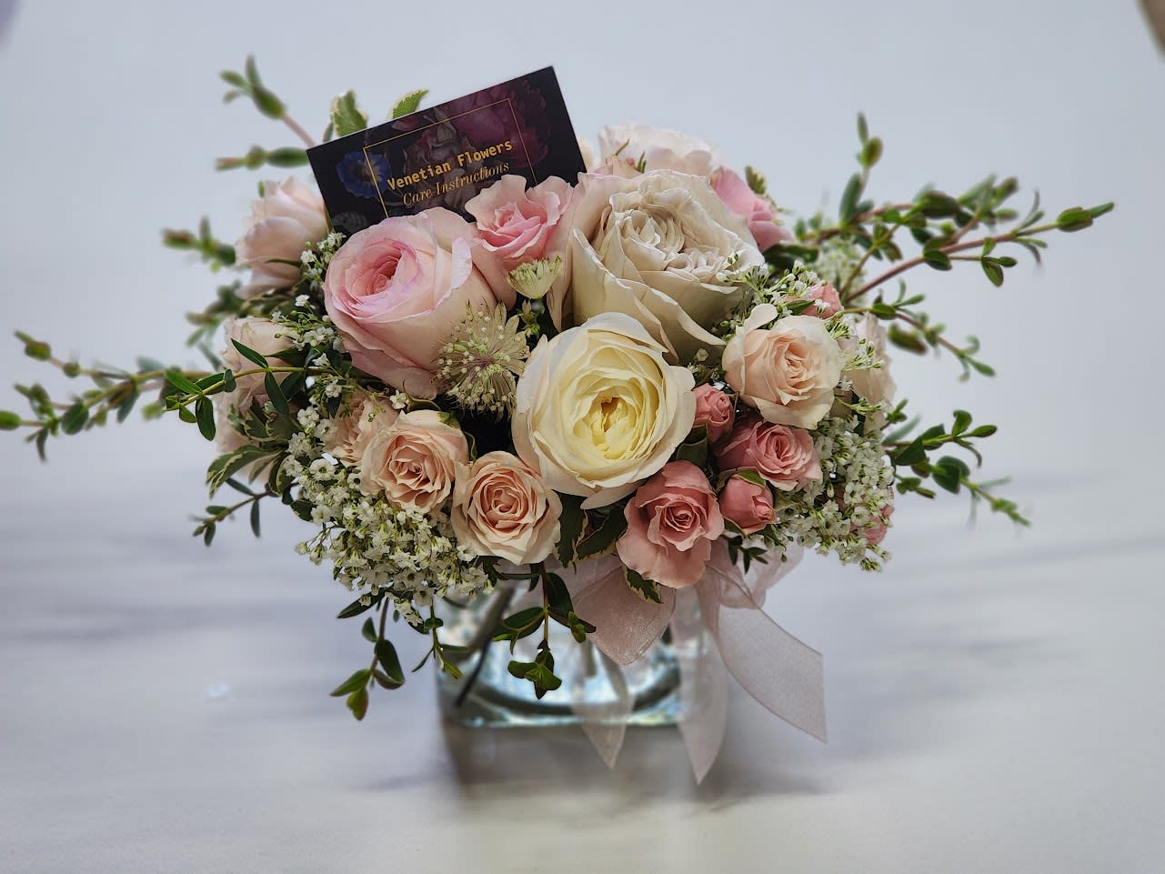Pink and cream rose bouquet in a glass vase with a ribbon