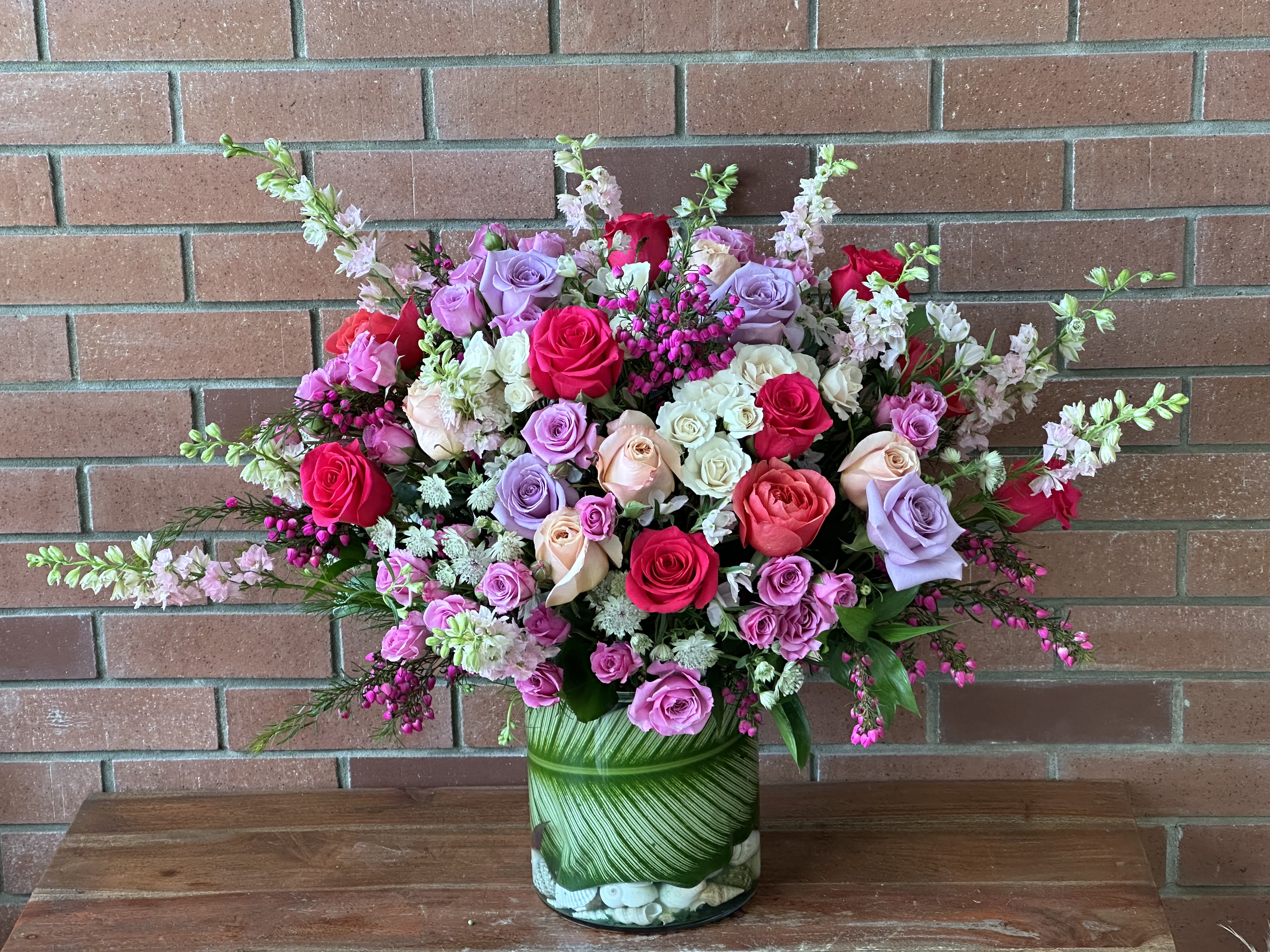 Mixed pink, lavender, and white roses in a glass vase