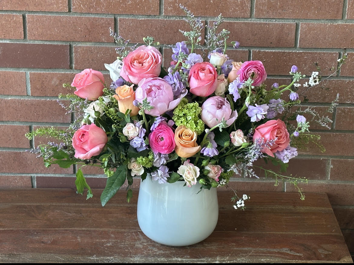 Pink and lavender flower arrangement in a pale blue vase