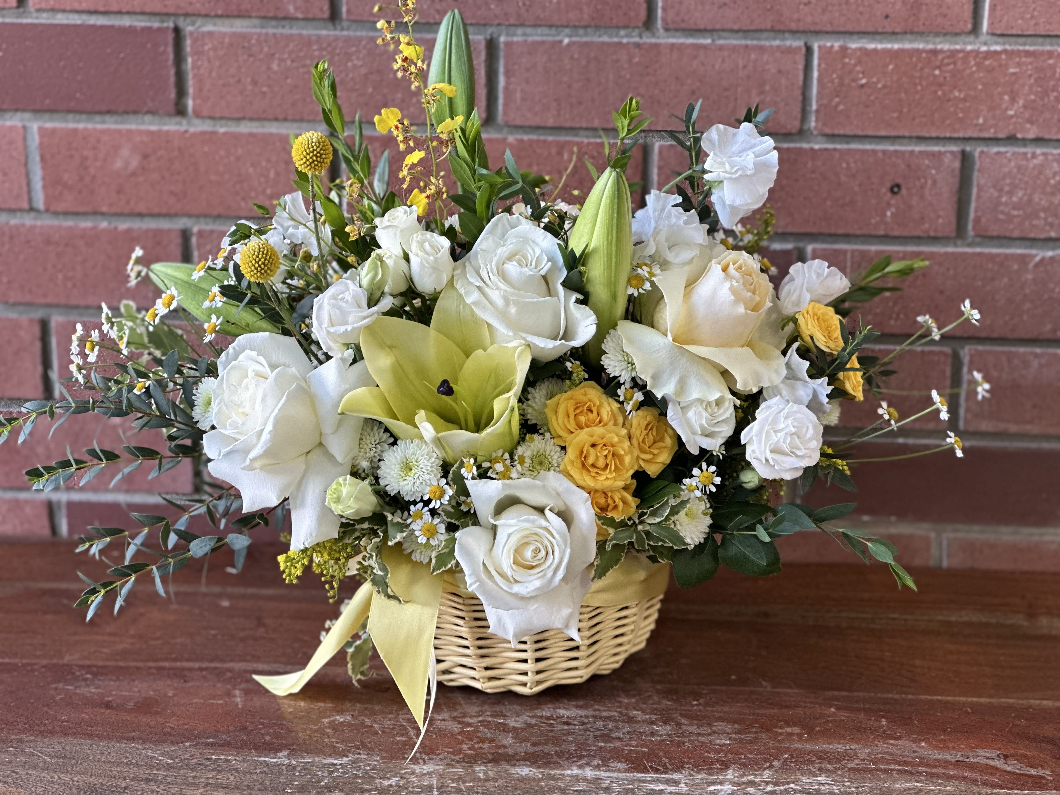 Basket arrangement of white and yellow flowers with a ribbon