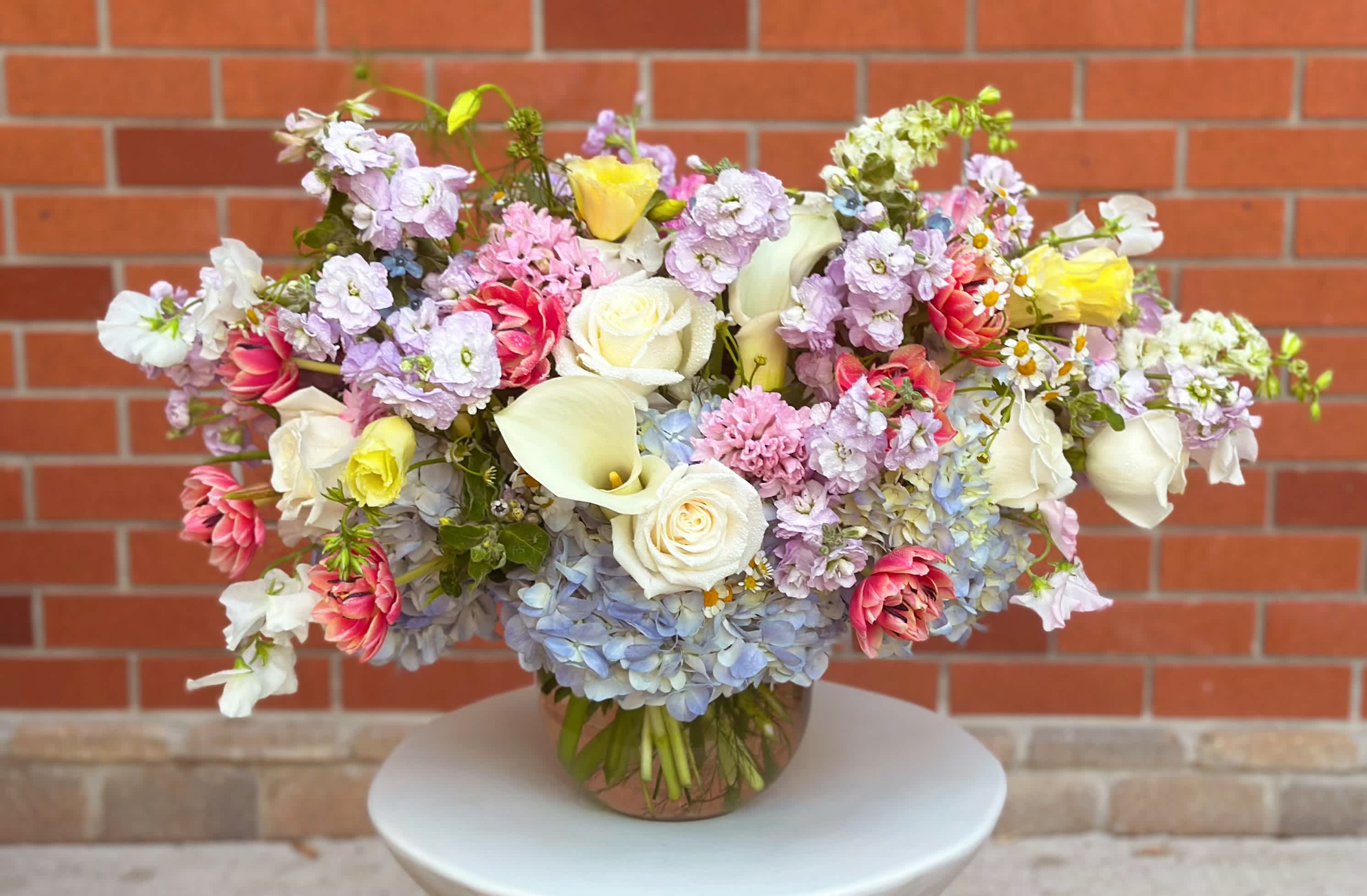 Mixed pastel bouquet in a round vase with roses, calla lilies, and hydrangeas