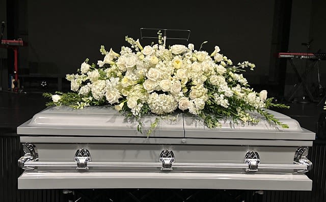 White floral casket spray on a silver casket