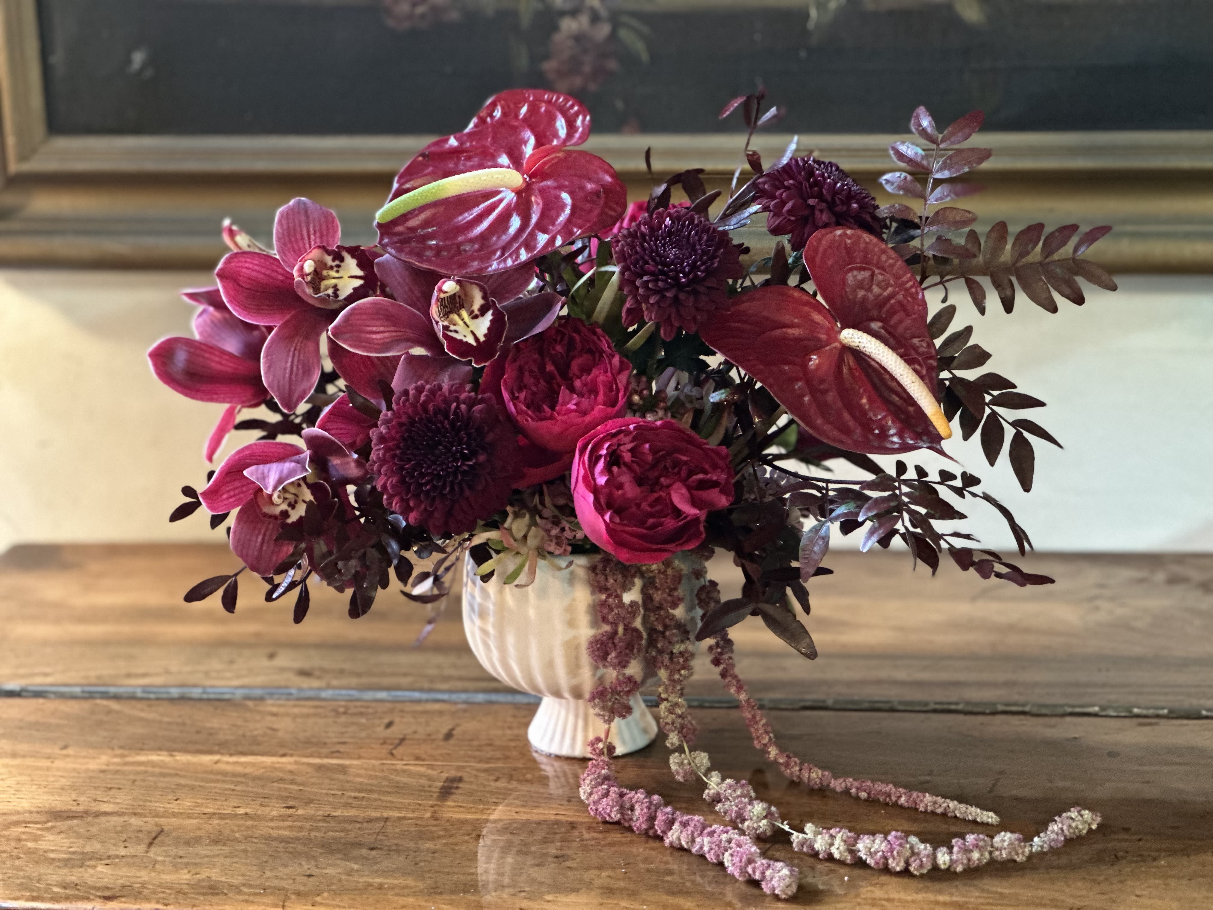 Magenta floral arrangement in a white vase with trailing blooms