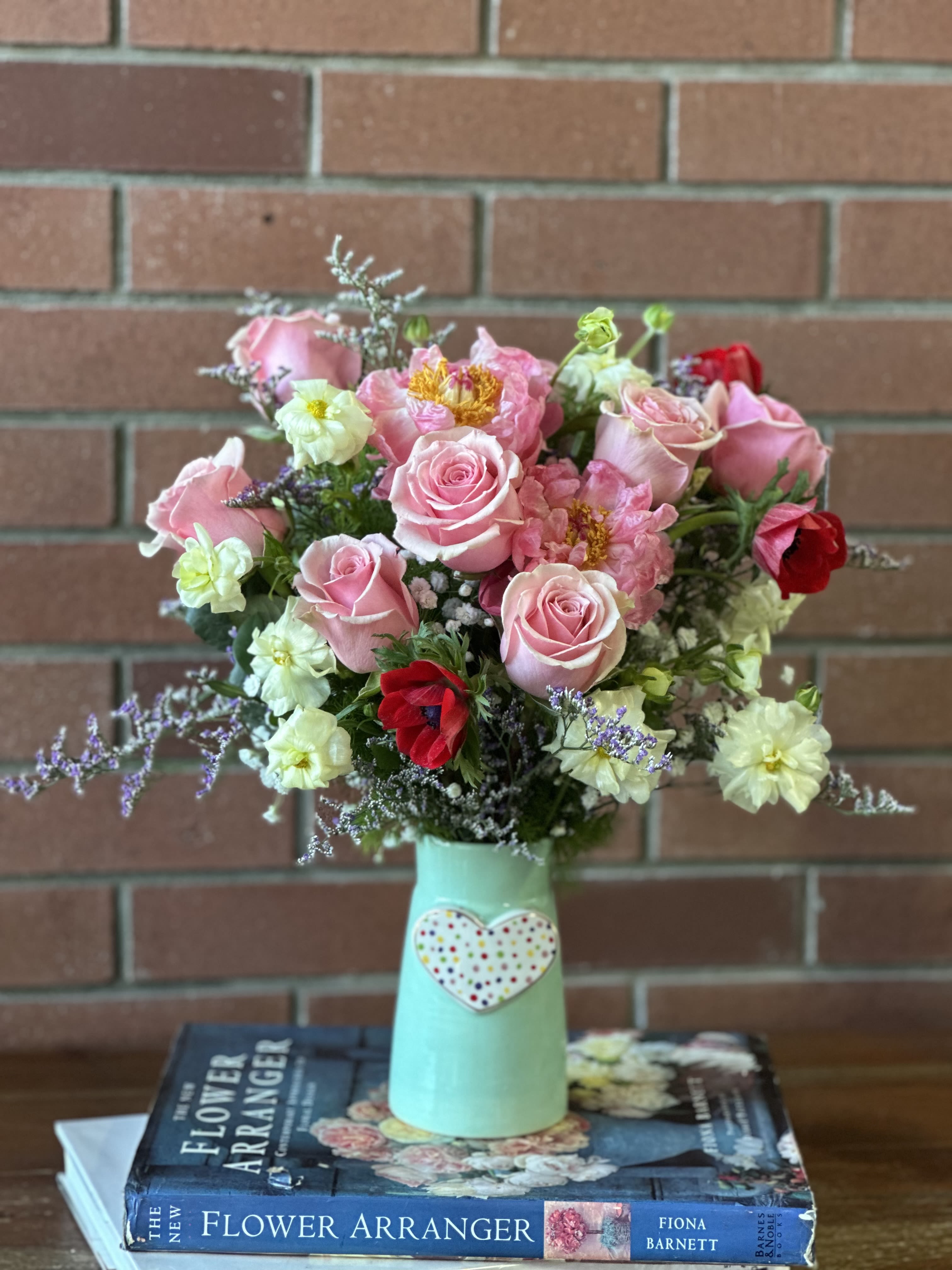 Pink roses and mixed flowers in a mint vase with a heart decoration