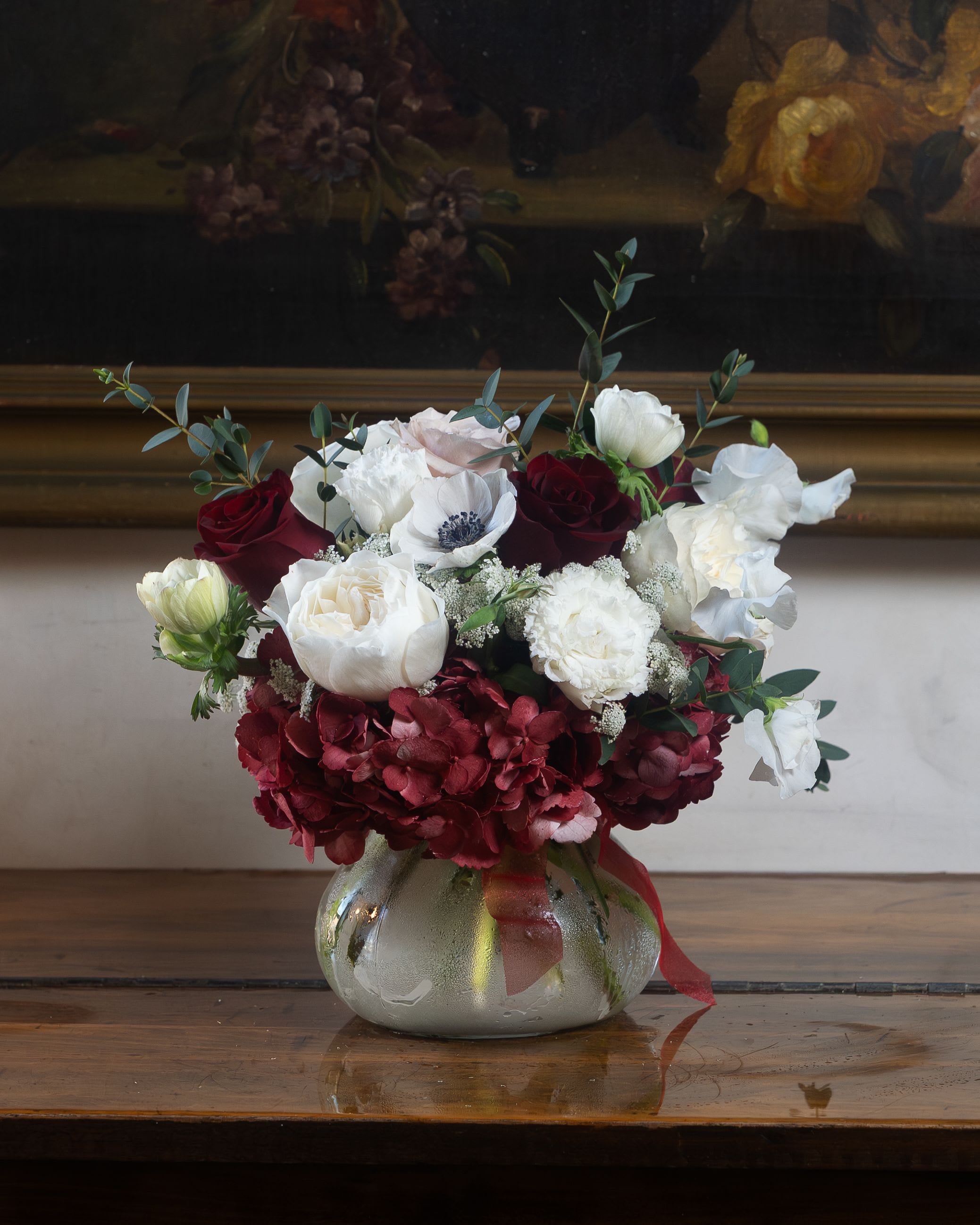 Bouquet of red and white flowers in a round glass vase