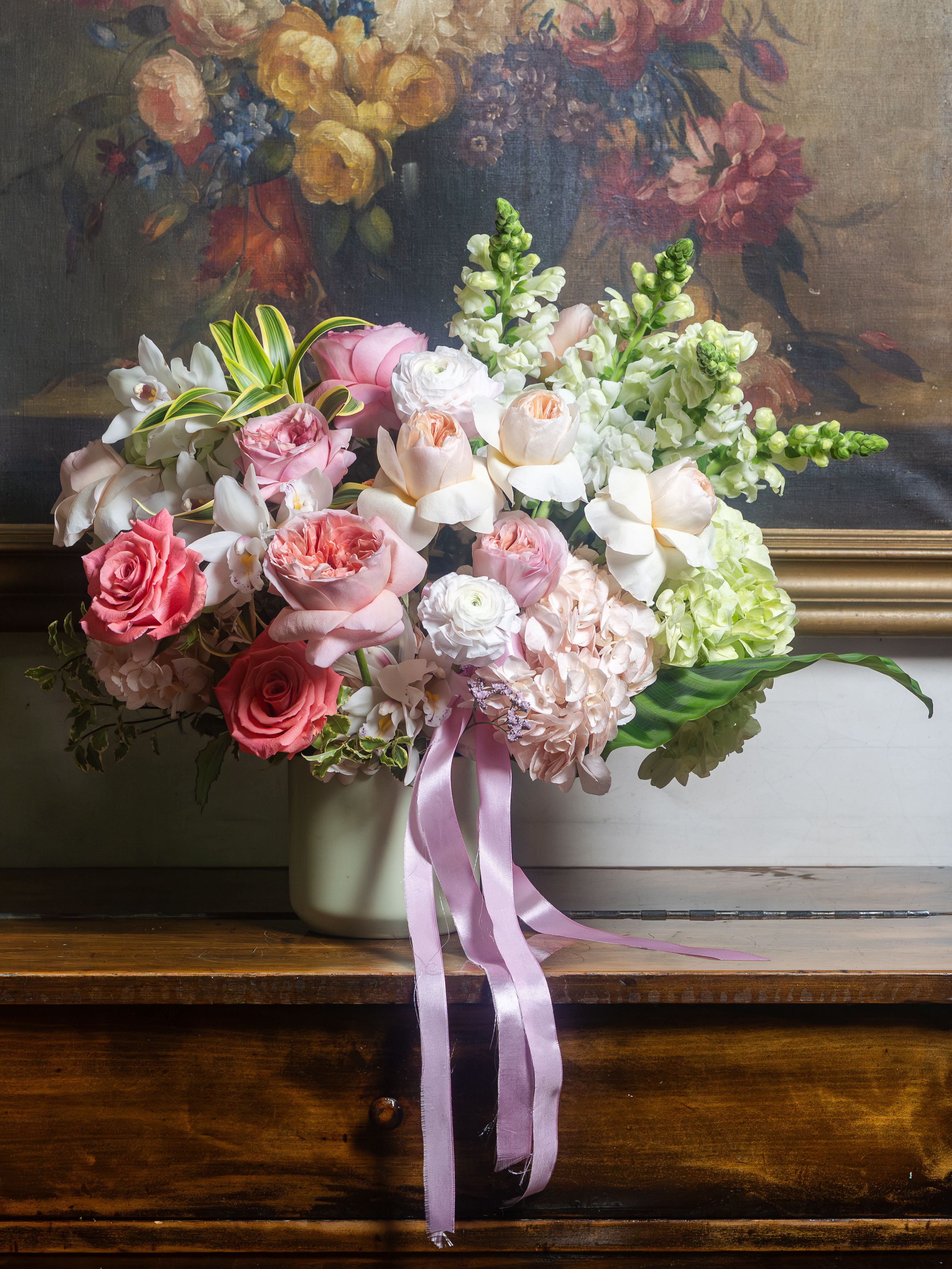 Belle Époque - Peach David Austin roses — the most coveted bloom in the world of flowers — open in full, layered perfection, the way only something truly extraordinary does. Blush and pink garden roses spill over one another in romantic abundance, soft as every memory she made for you. Bright pink roses bring warmth and joy, because she always did. Lime green hydrangeas ground it all in garden-fresh lushness, and white orchids — delicate, rare, and effortless — remind you of exactly who she is. Finished with a trailing lilac satin ribbon, this is not just a bouquet. This is thank you. This is I see you. This is every unsaid thing finally said in flowers.