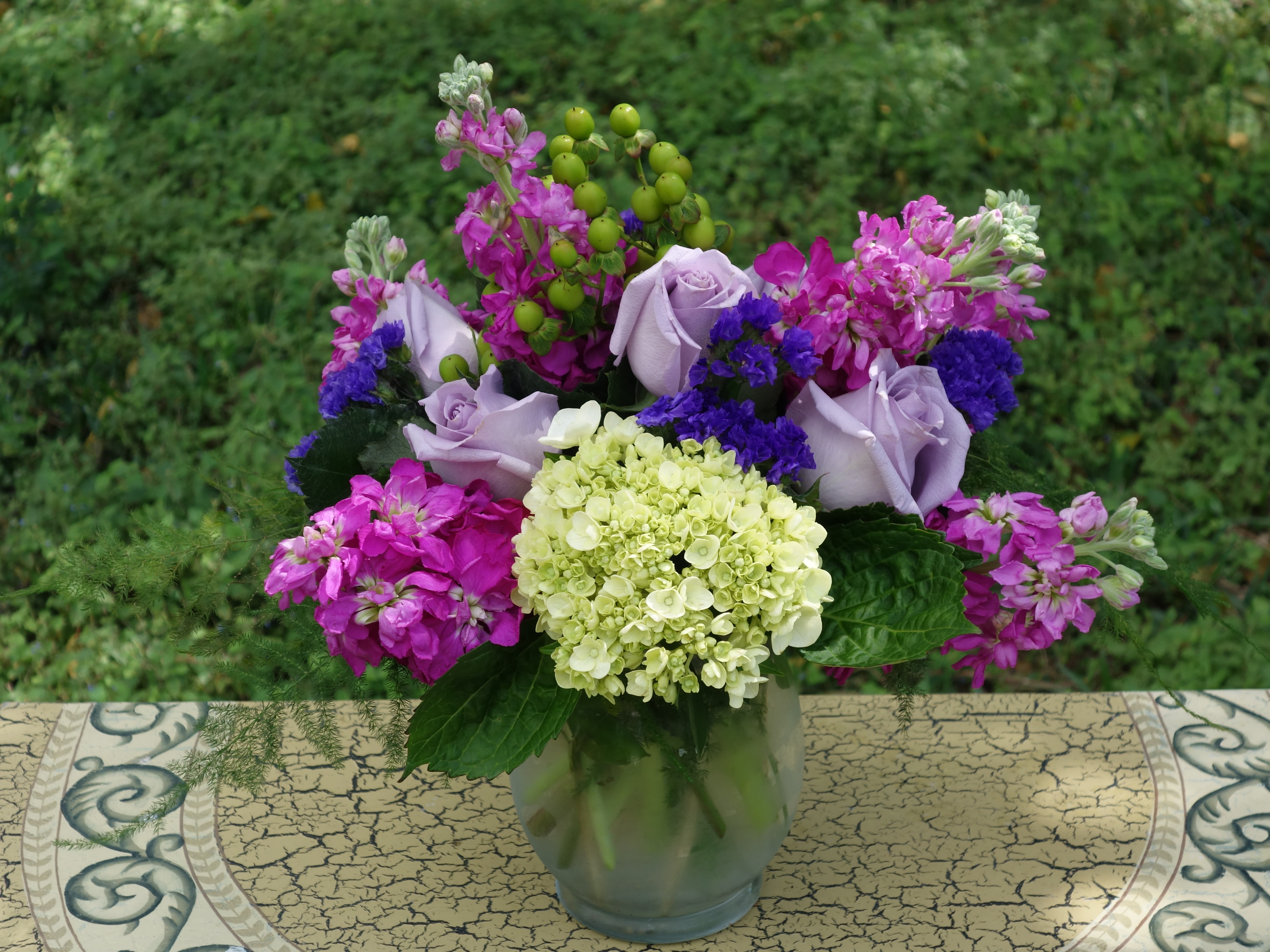 Lavender roses and pink-purple flowers in a glass vase