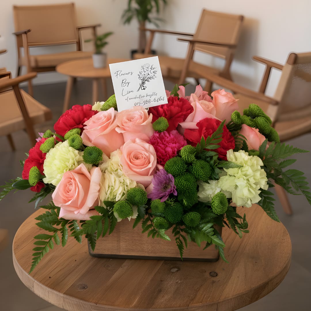 Mixed pink and red flower arrangement in a low rectangular box
