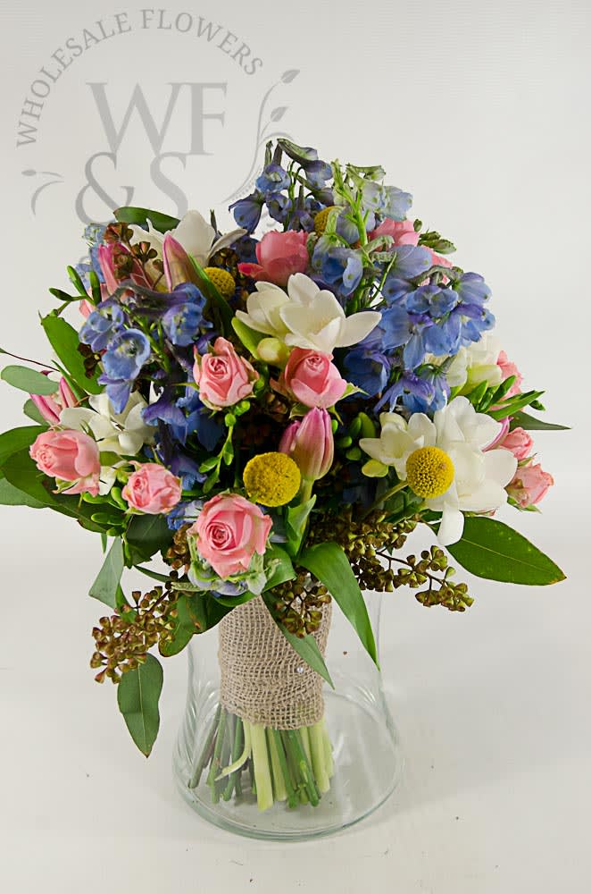 Mixed bouquet of pink, white, and blue flowers in a glass vase